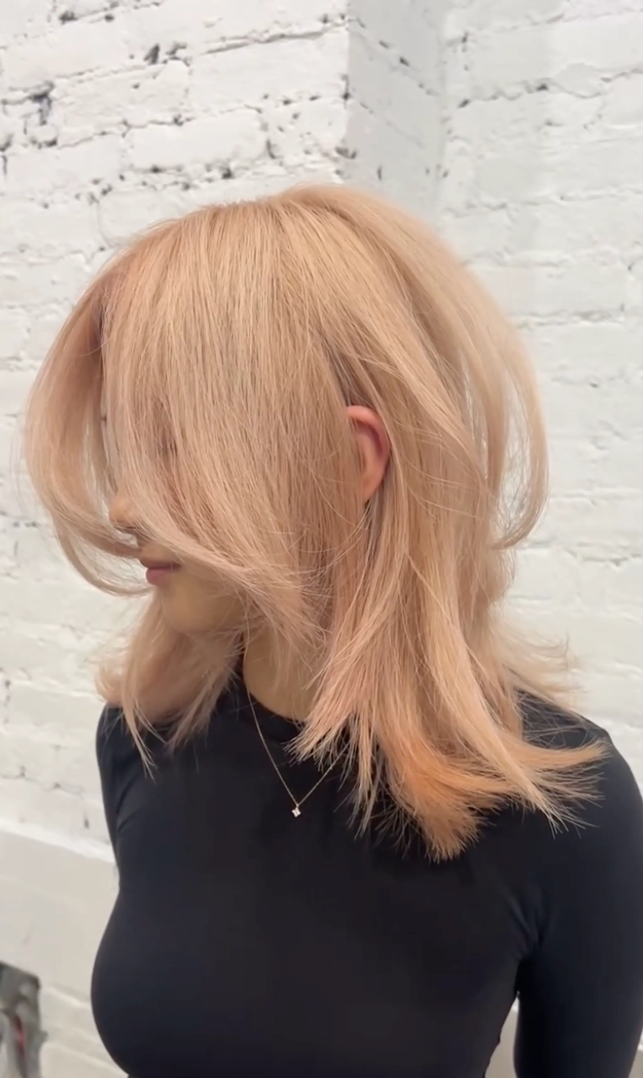 Medium-length champagne blonde hair with voluminous face-framing layers, soft texture, and feathered ends.