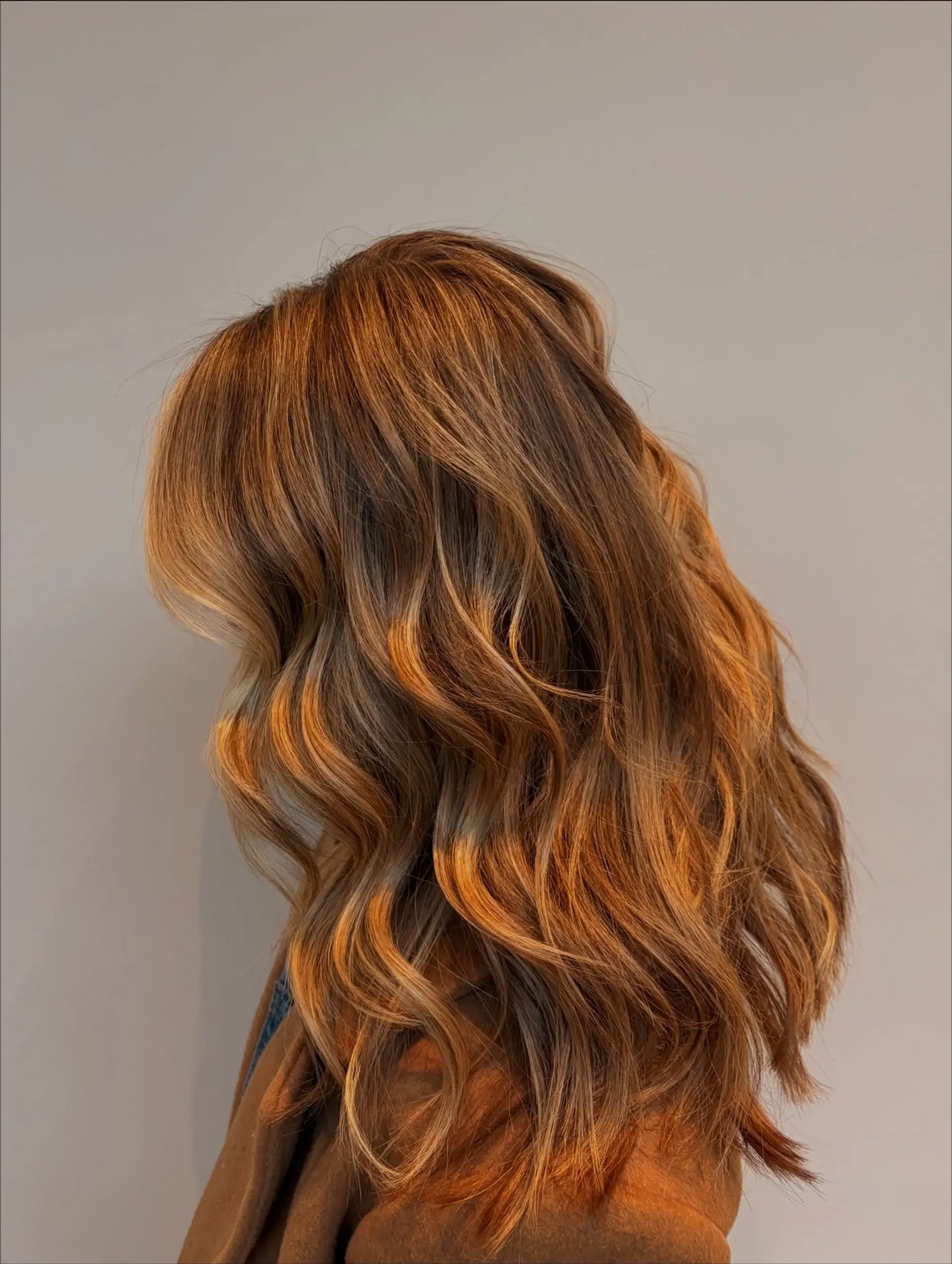 Long, warm dimensional brunette hair styled into soft, flowing loose waves with subtle caramel and honey highlights. 1