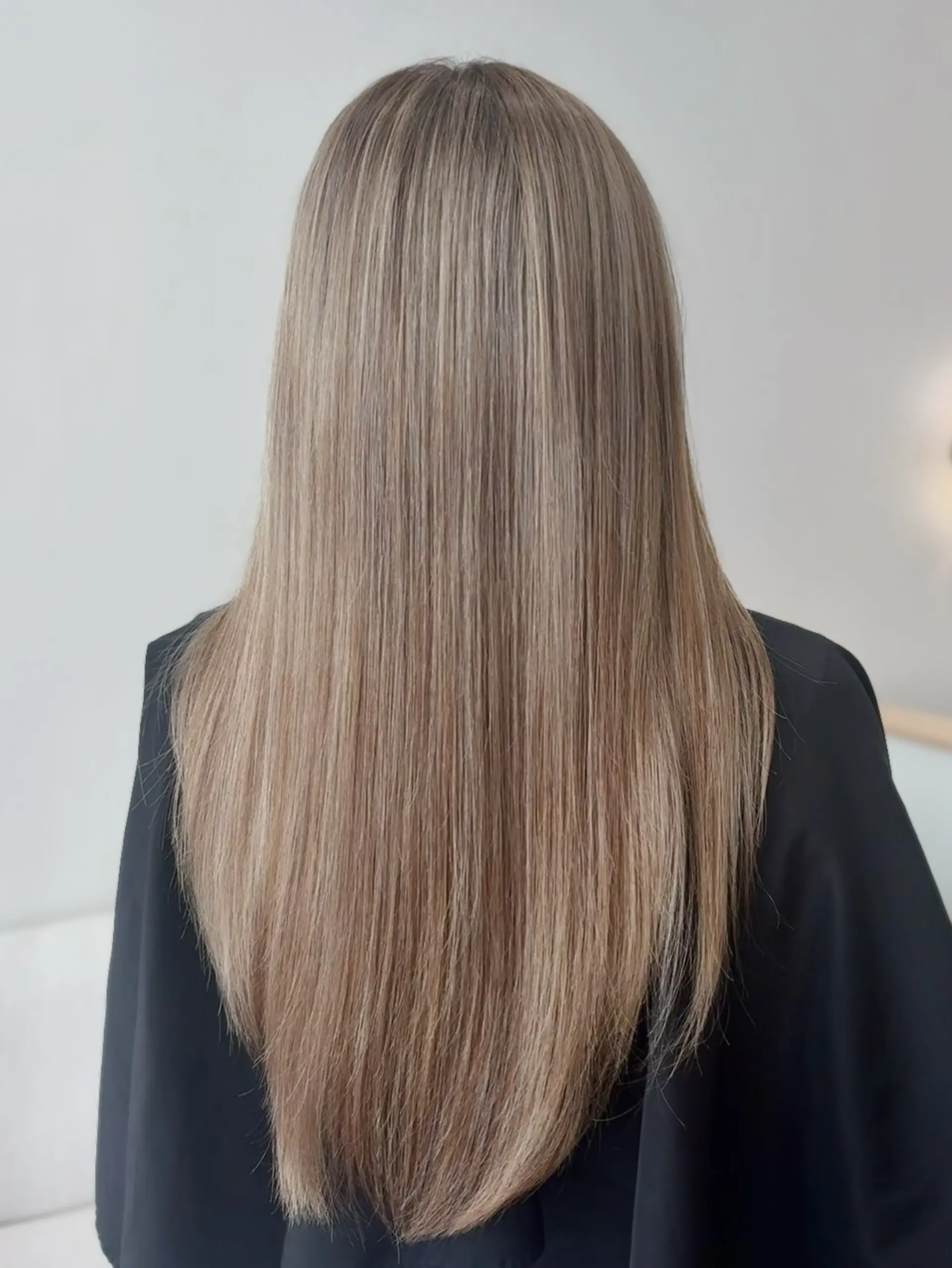 Long, sleek straight hair finished with a subtle V-cut shape, showcasing a finely blended teddy bear blonde color. 1