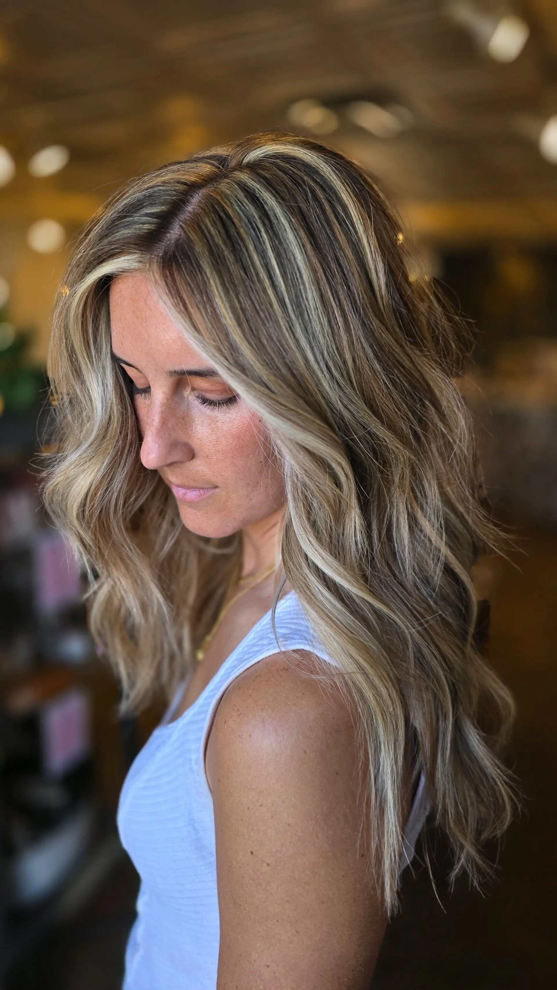 Long hair featuring bright blonde surface highlights blended seamlessly over a darker brunette base, styled in loose, lived-in waves. 1