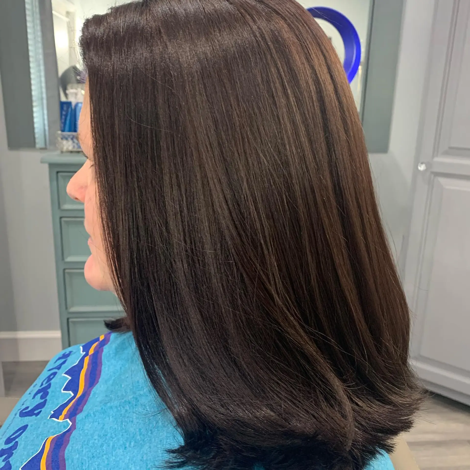 A glossy, collarbone-length dark chocolate brown lob styled sleek and straight with softly under-beveled ends. 1