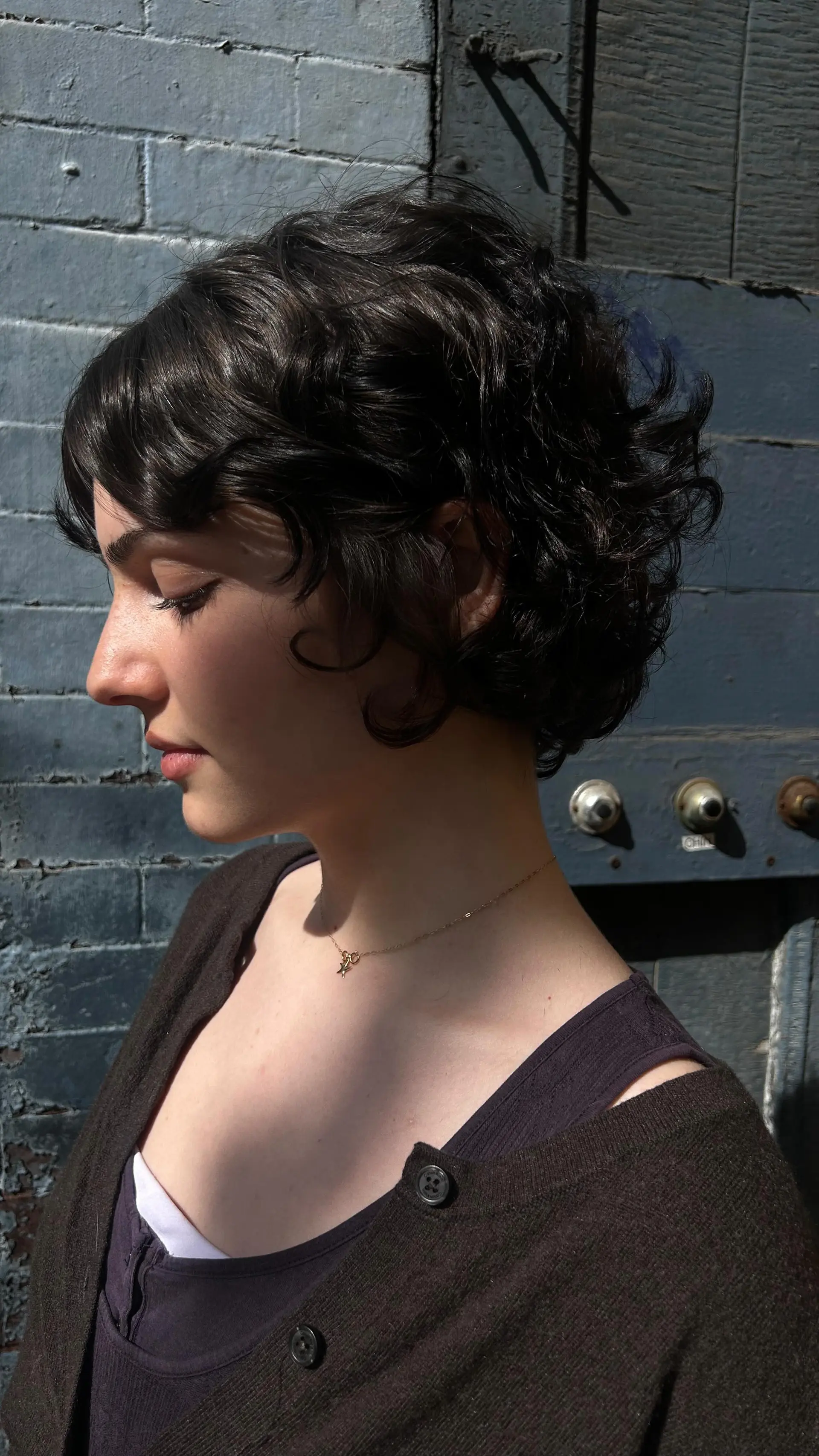 A textured curly bixie cut featuring soft, layered waves, short face-framing fringe, and flipped-out curl definition at the nape. 1