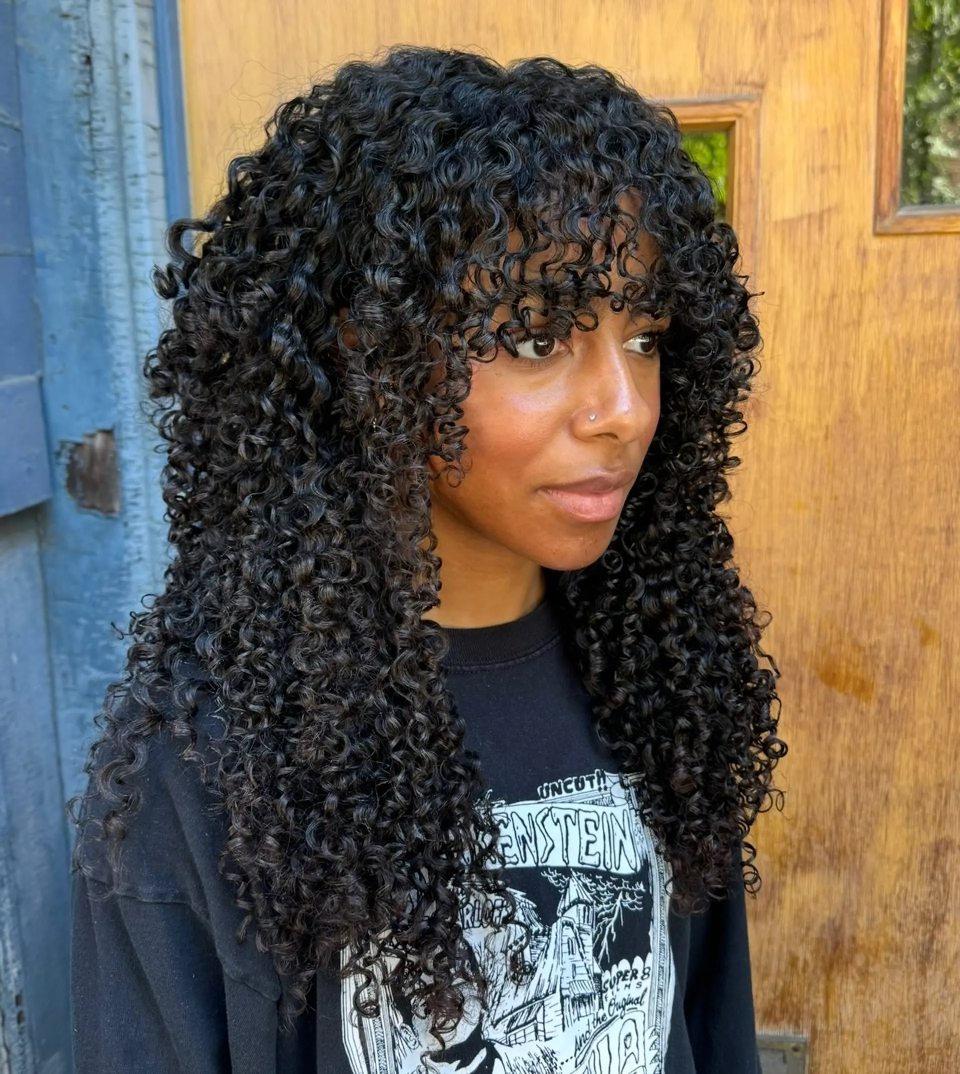 Defined tight spiral curls styled into a soft layered shag with textured curly bangs. 1