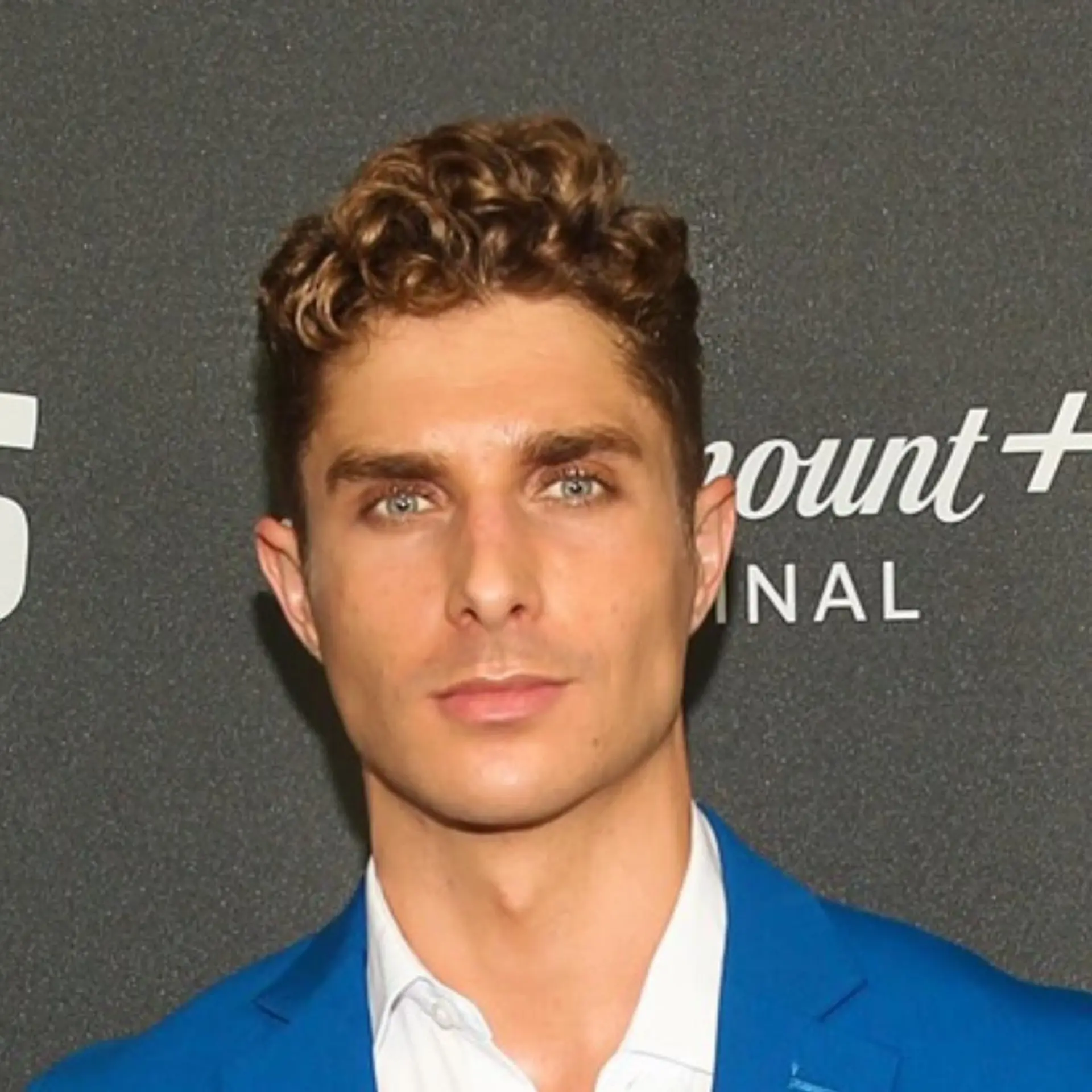 A short men's haircut featuring natural, defined curls on top styled upward and slightly back, paired with neatly tapered sides. 1