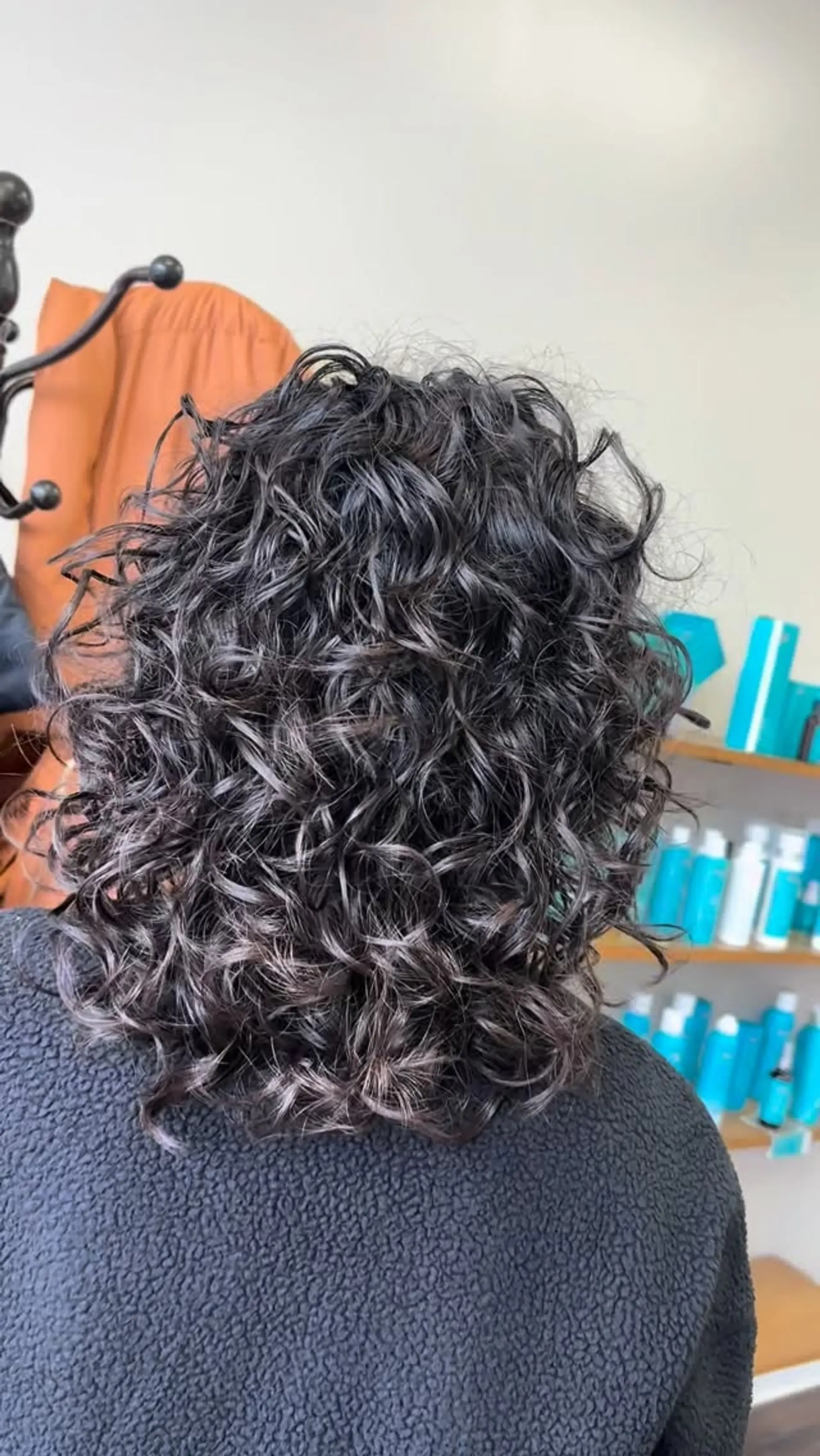 Medium-length haircut styled with defined, bouncy dark natural curls. 1