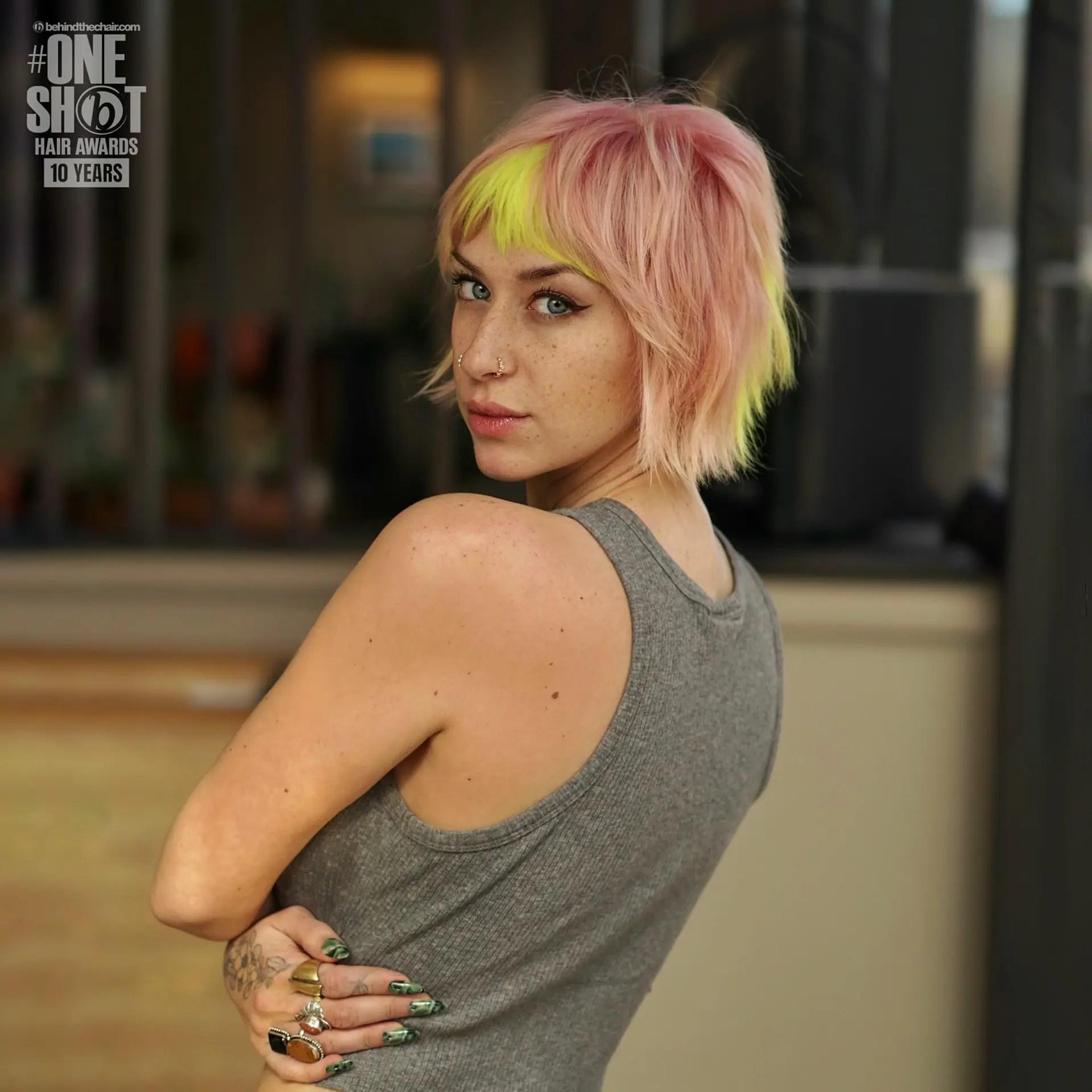 A choppy, textured pastel pink bixie cut highlighted with vibrant neon yellow bangs. 1