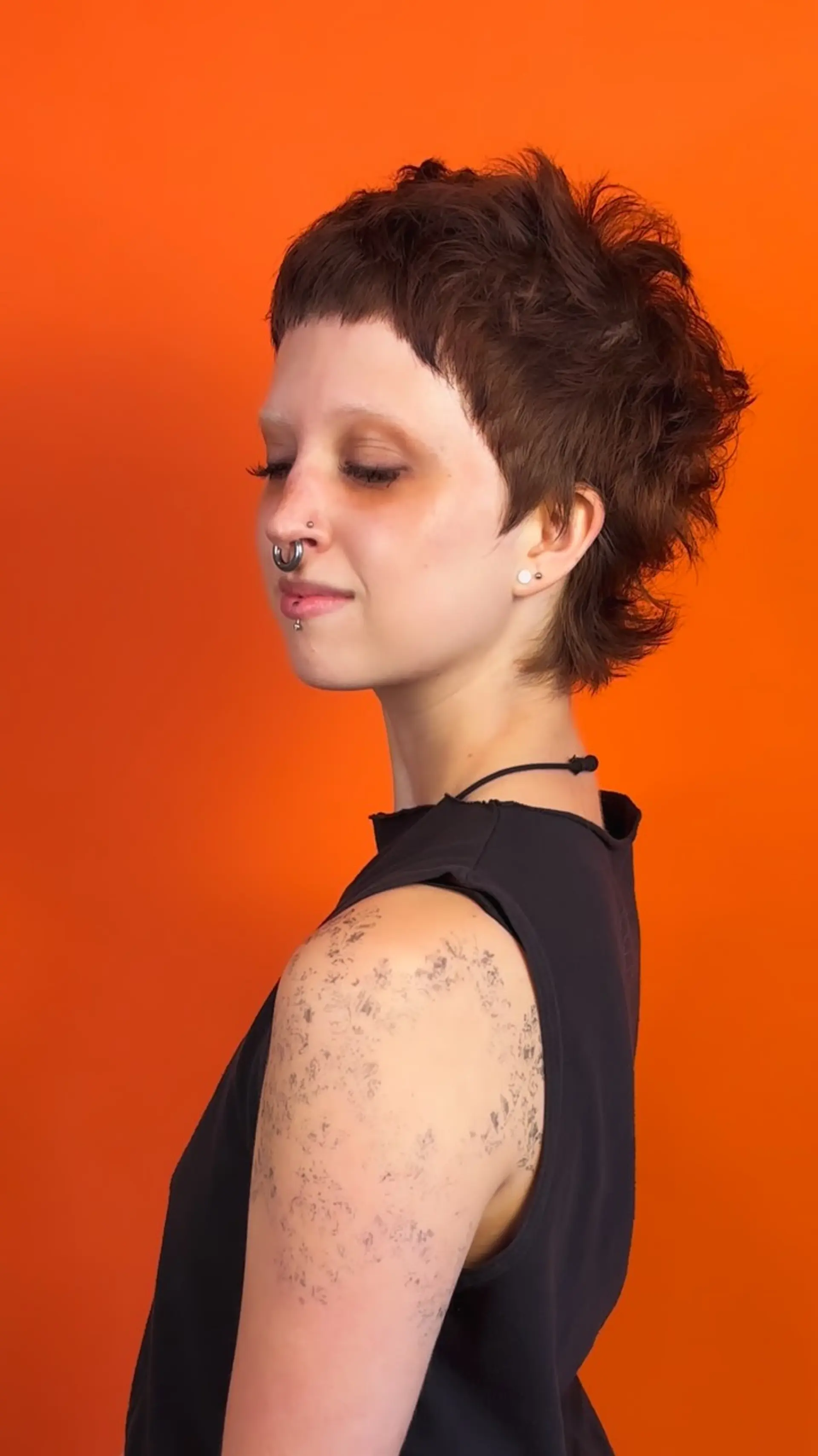 A shaggy, textured pixie mullet featuring blunt micro bangs and soft, piecey layers extending around the ears and nape. 1