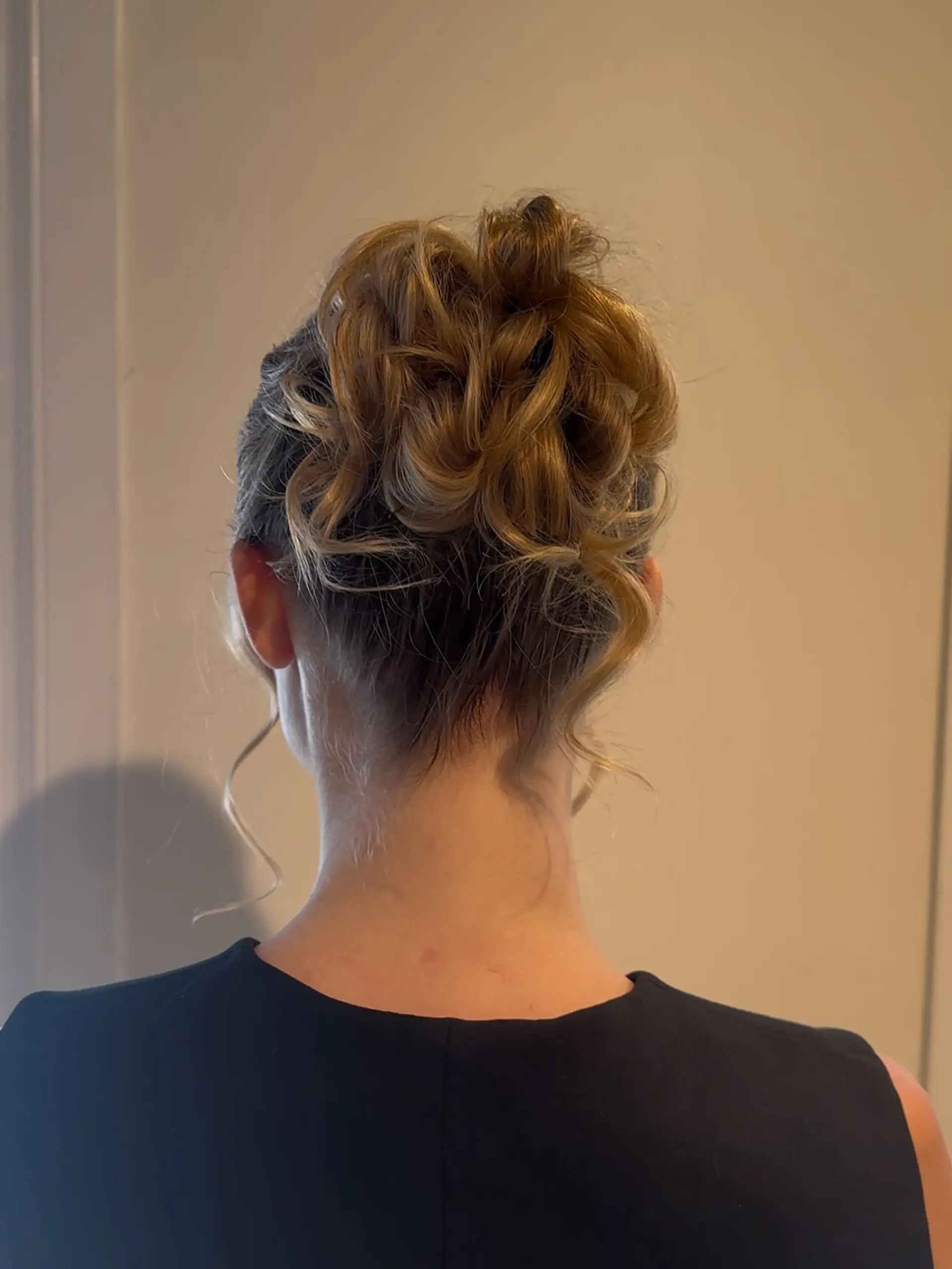 An elegant updo featuring gathered soft curls pinned high at the crown with delicate loose tendrils. 1