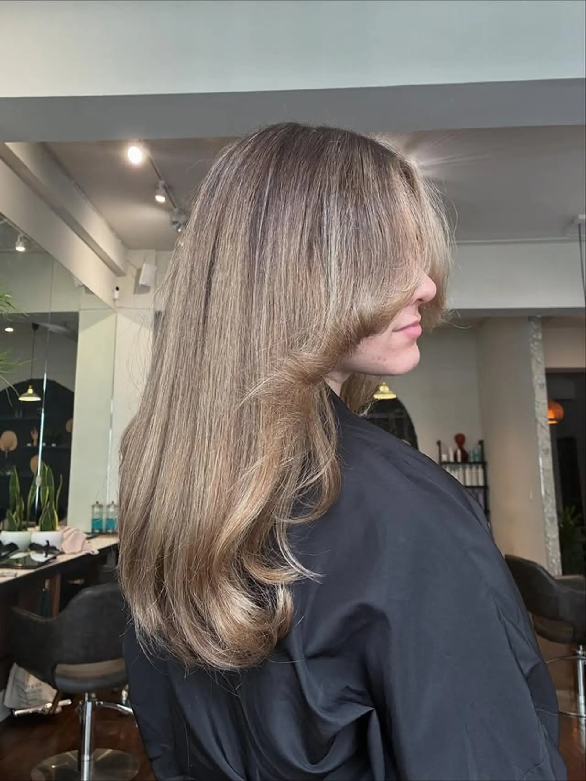 Long layered haircut with face-framing curtain bangs. 1