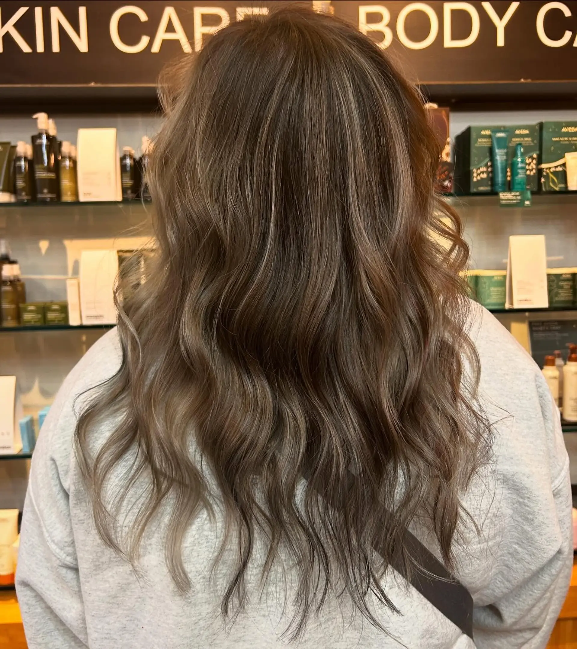 Long hair cut with soft texturing and styled into effortless, loose waves, showcasing a blended cool ash-toned balayage. 1