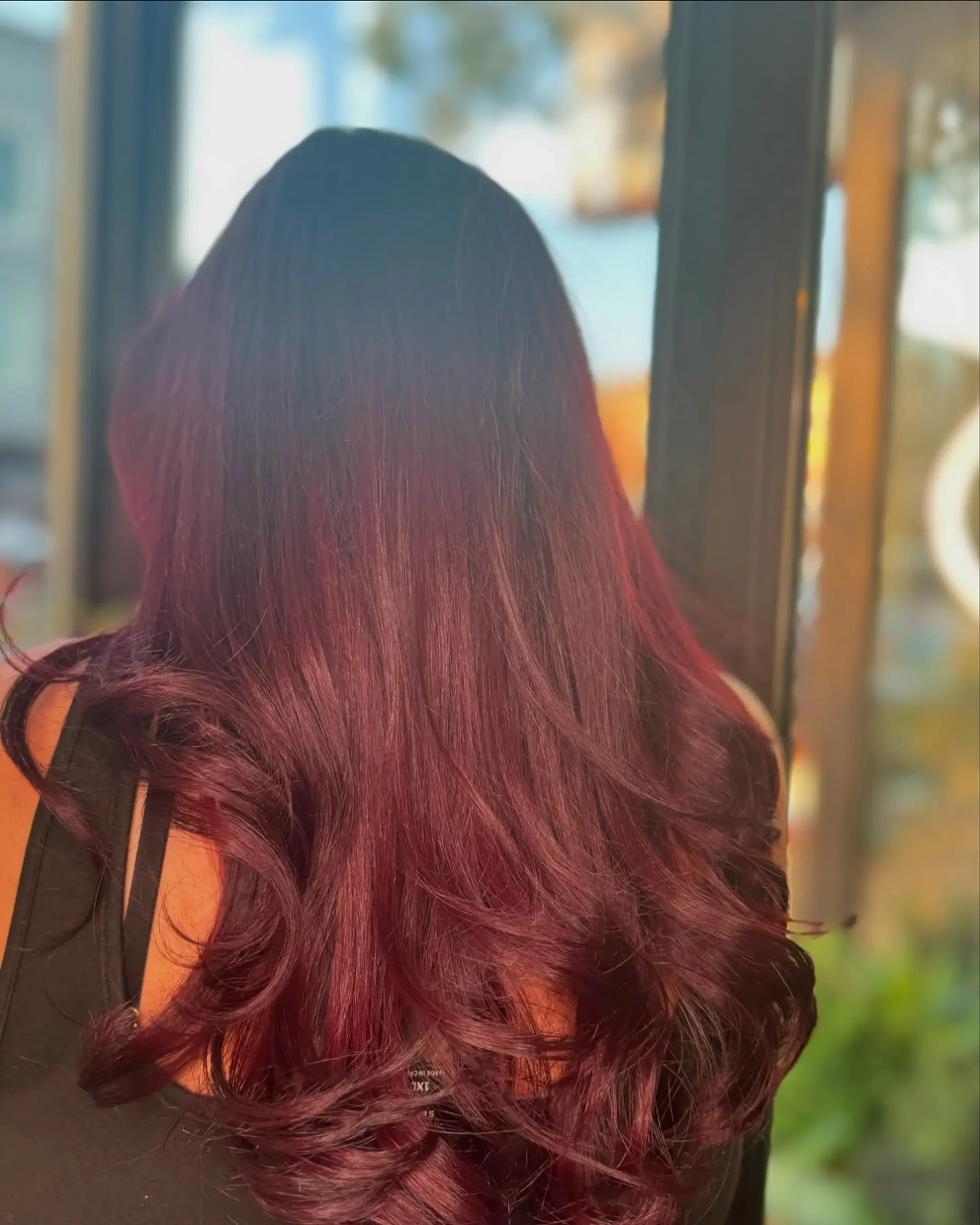 Long, vibrant mahogany hair cut in soft layers and styled with smooth, voluminous curls at the ends. 1