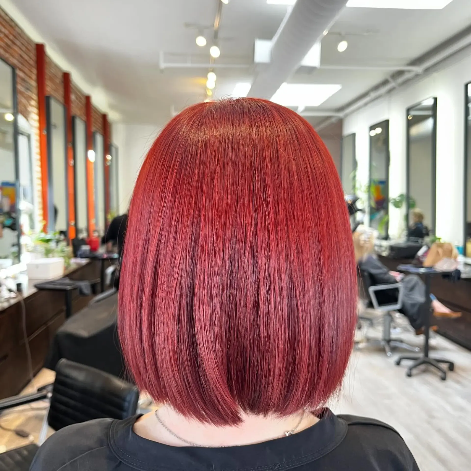 A sleek, straight blunt bob colored in an all-over vibrant ruby red tone. 1