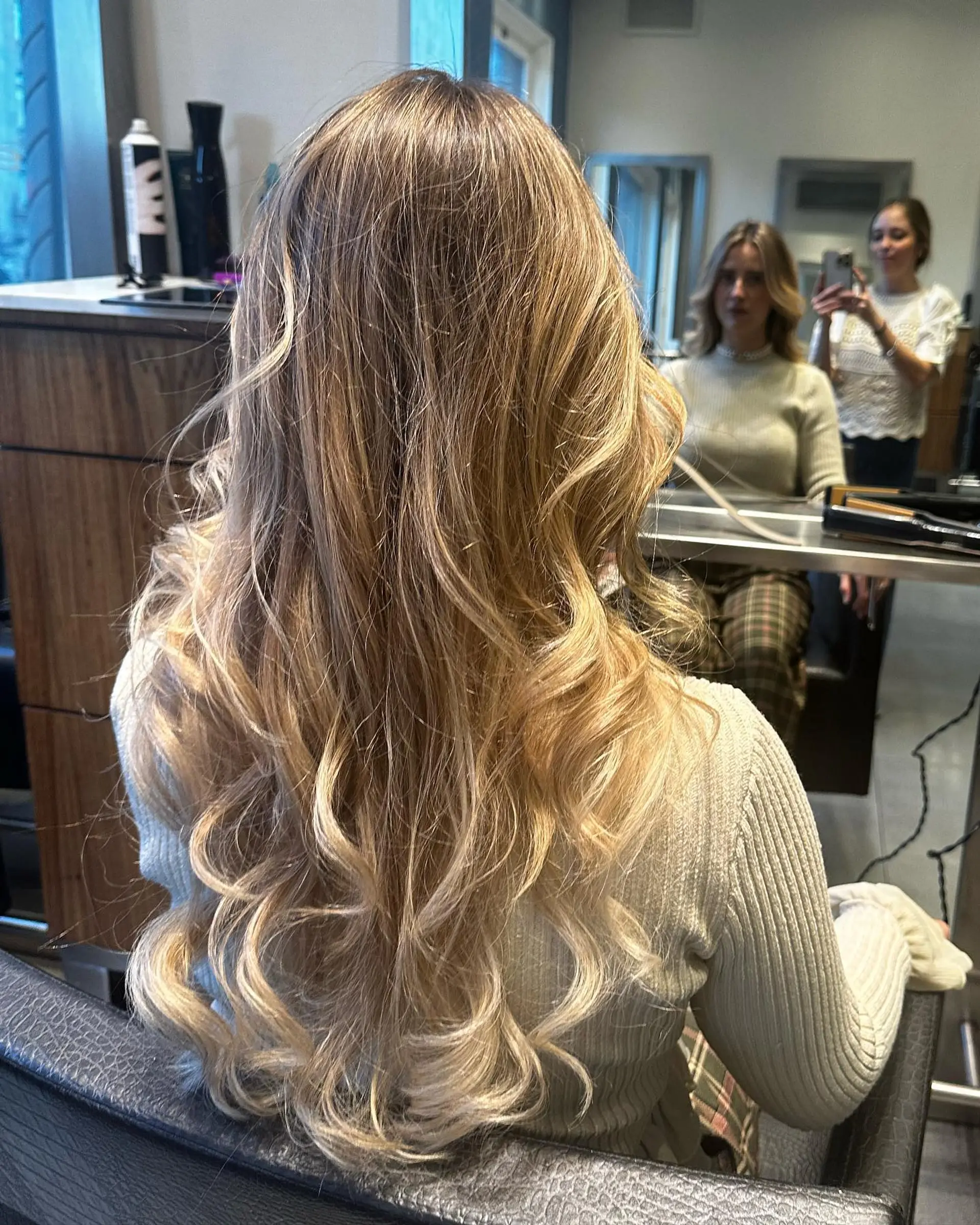 Long multi-tonal blonde hair styled into flowing, soft curls and loose waves. 1