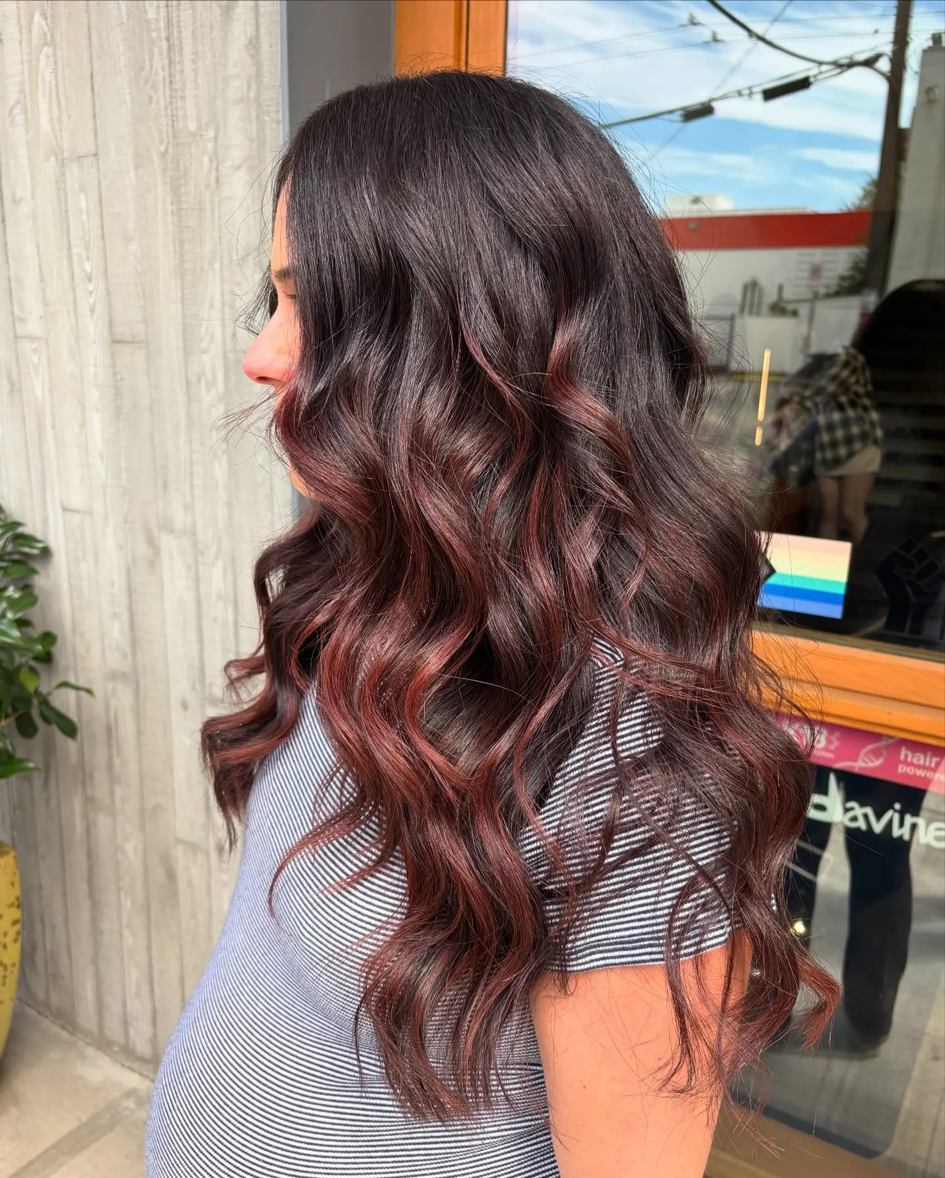 Long dark brown hair styled in soft loose waves with vibrant wine red and burgundy balayage highlights. 1