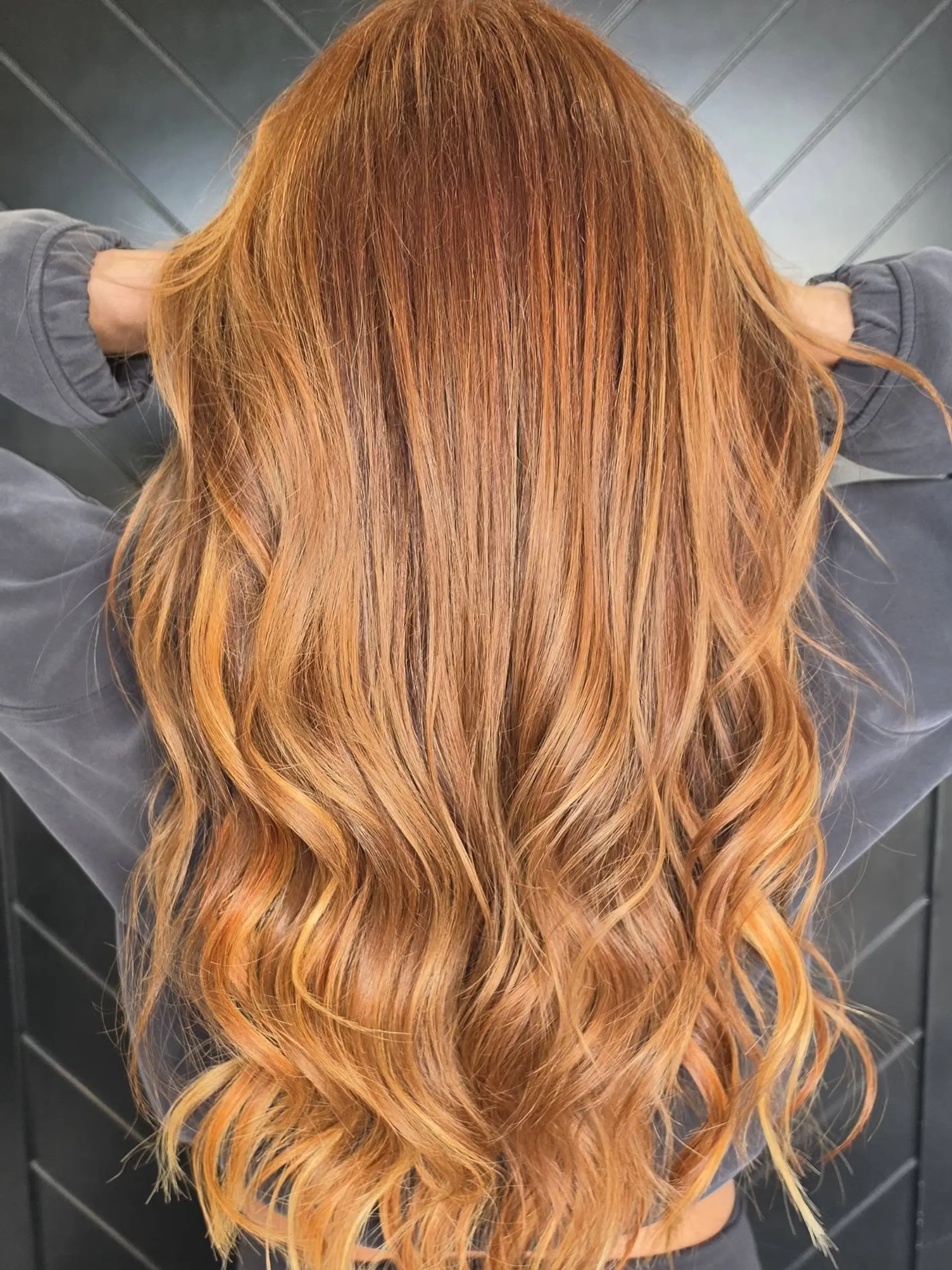 Long dimensional pumpkin spice copper hair styled with smooth texture at the roots transitioning into loose, cascading waves. 1