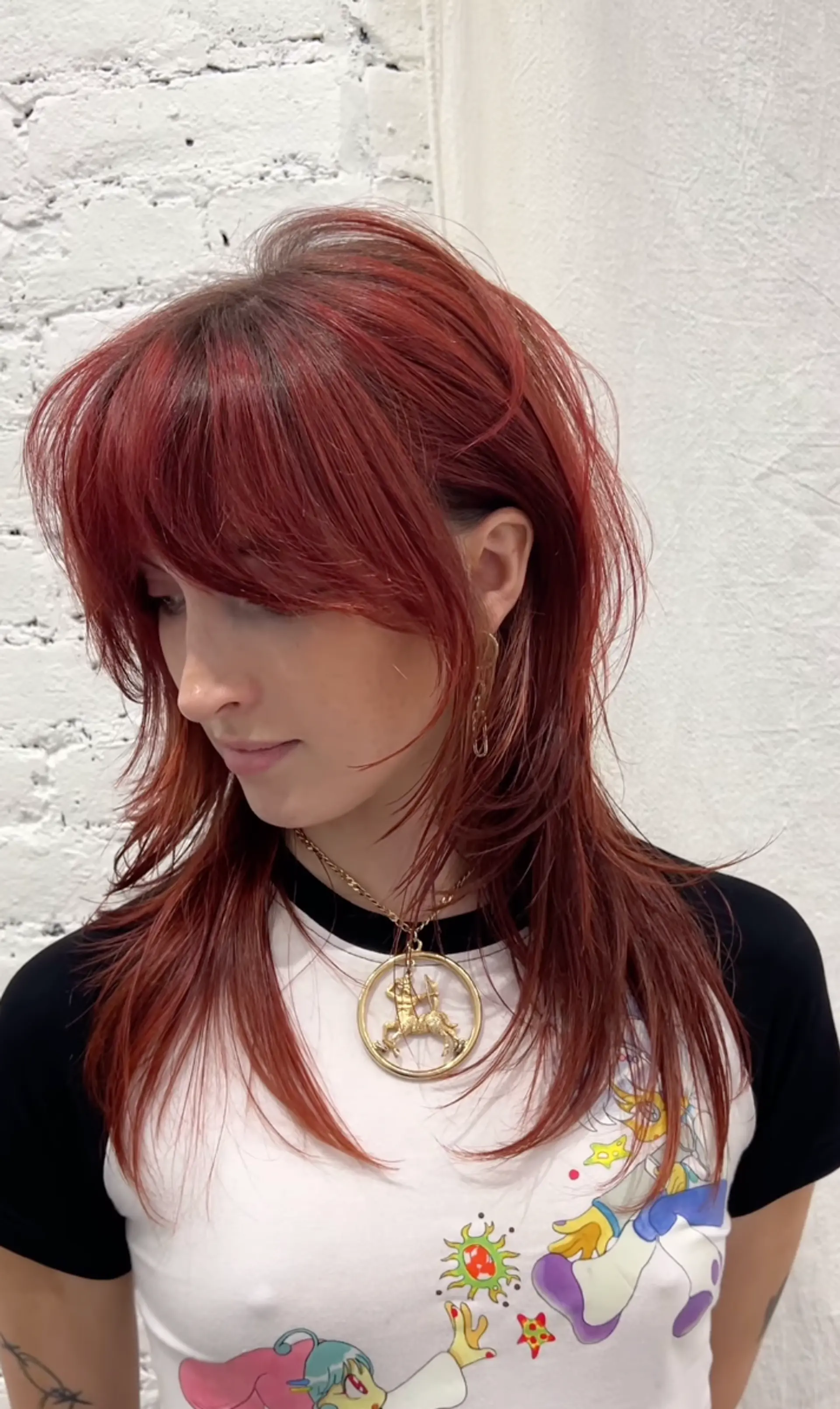 A long, layered cut with face-framing strands and curtain bangs, featuring vibrant red and copper tones. 1