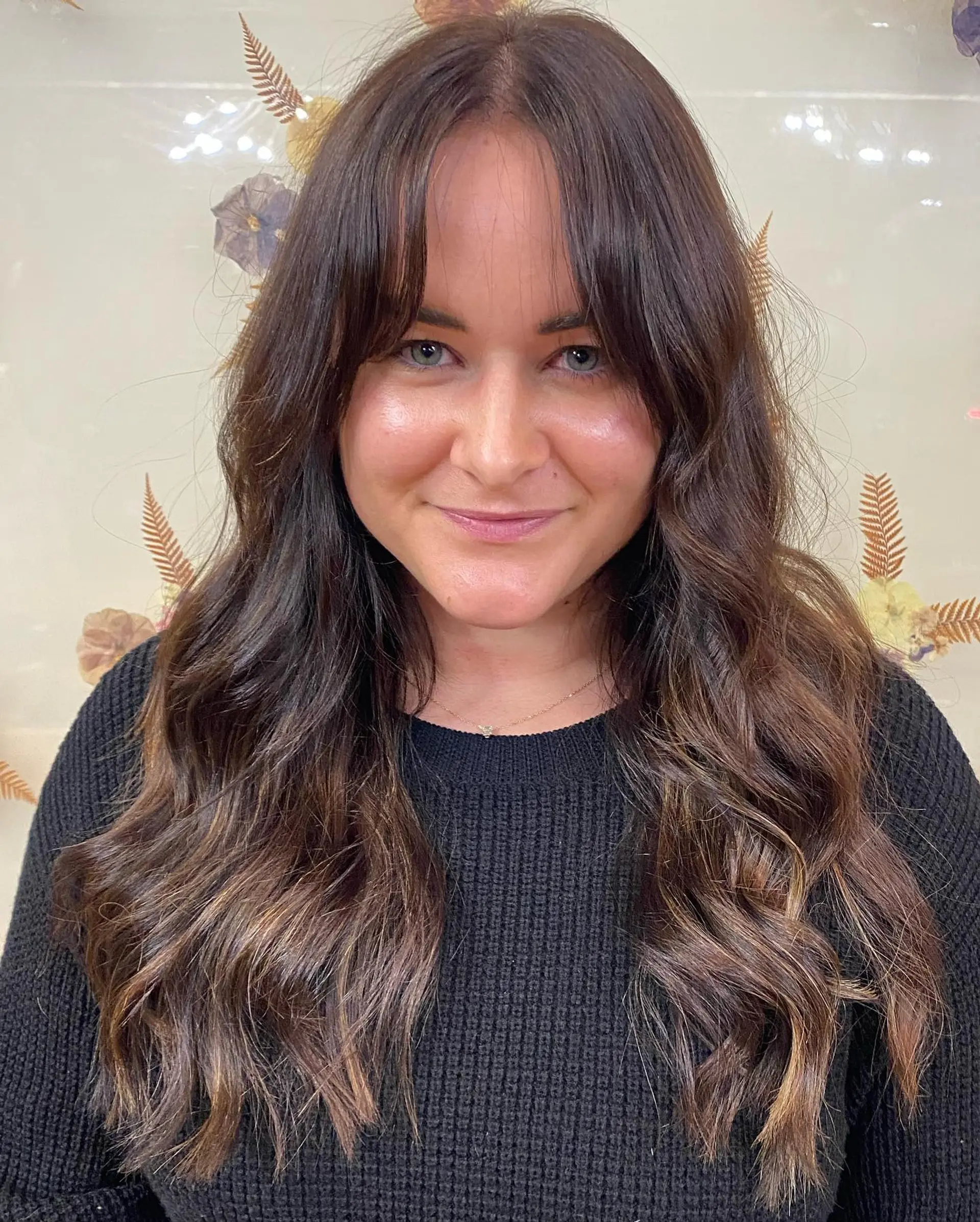 Long dark brunette hair styled with effortless loose waves and curtain bangs. 1
