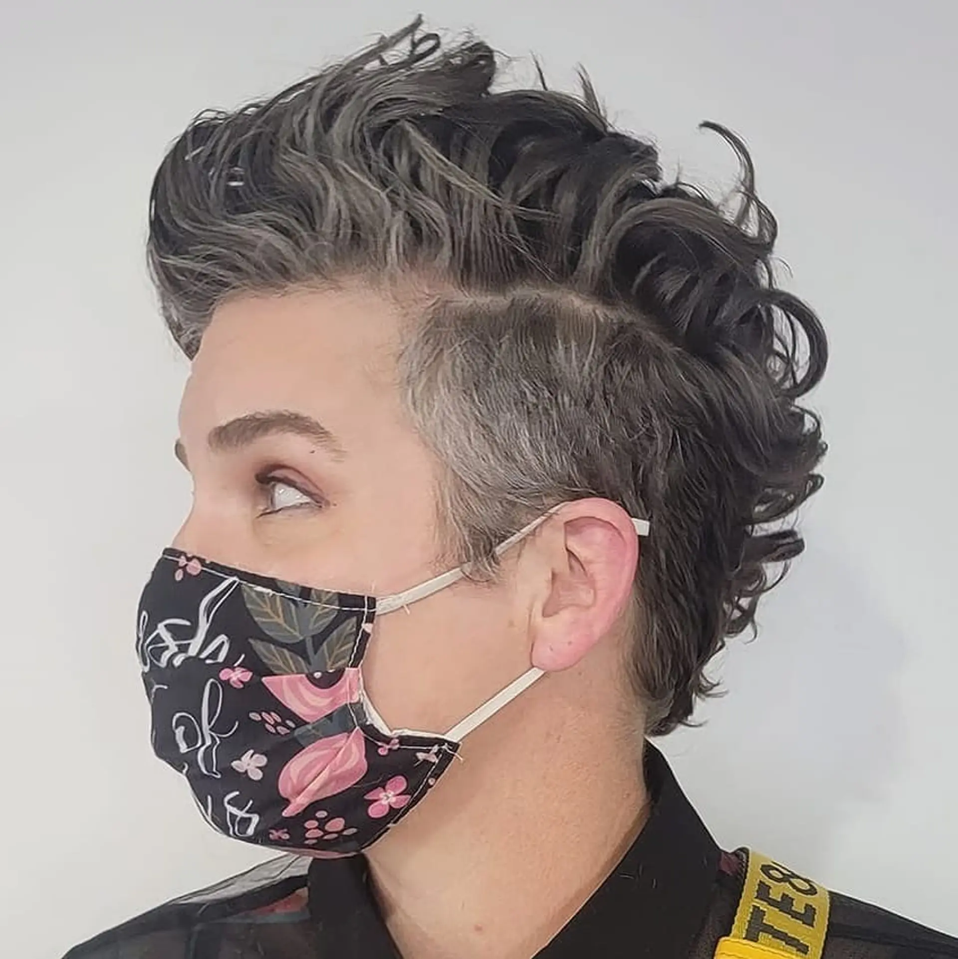 A voluminous curly quiff with an undercut, primarily in shades of gray and black, combining elements of taper and fade with a fuller, curly top. 1