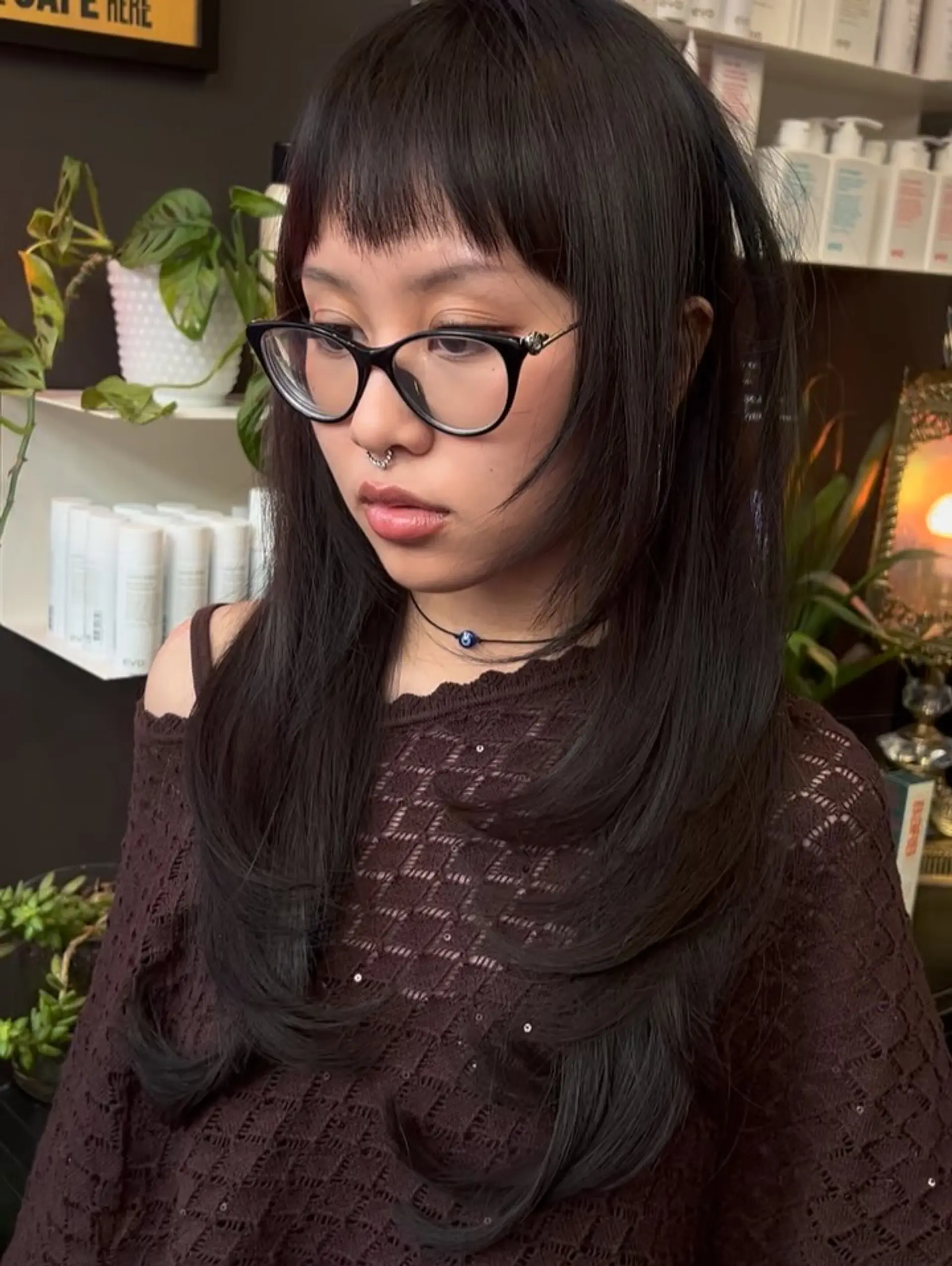 Long layered dark hair cut with textured micro bangs and face-framing feathered ends. 1
