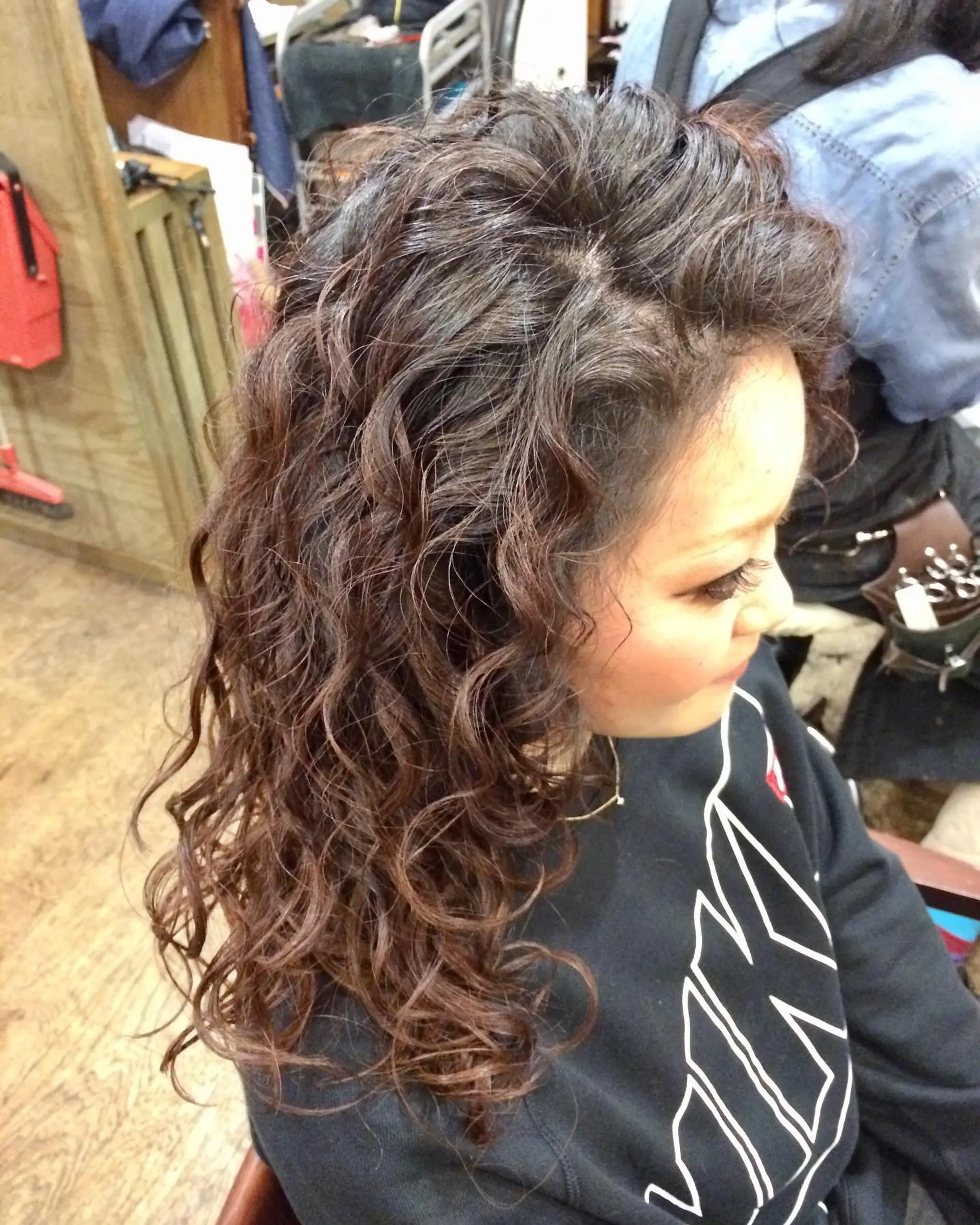 Full, bouncy spiral perm curls styled with defined ringlets on medium brown long hair. 1