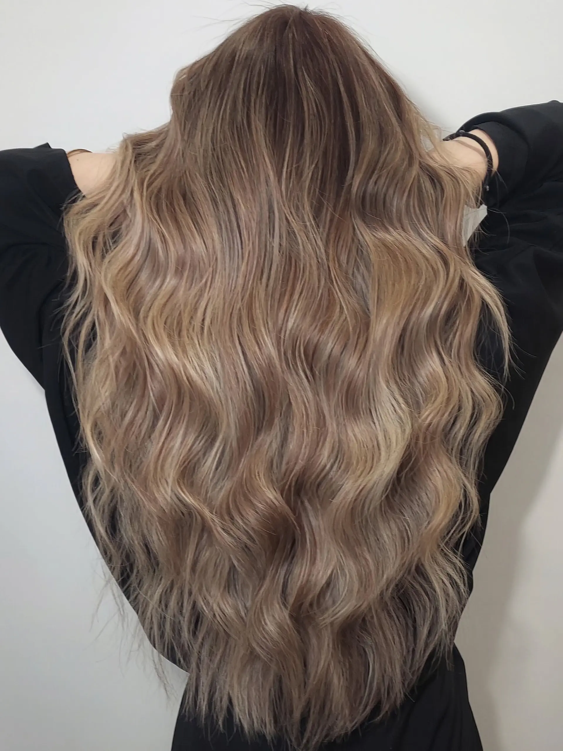 A long, wavy hairstyle featuring a blended beige brown foilayage color technique. 1