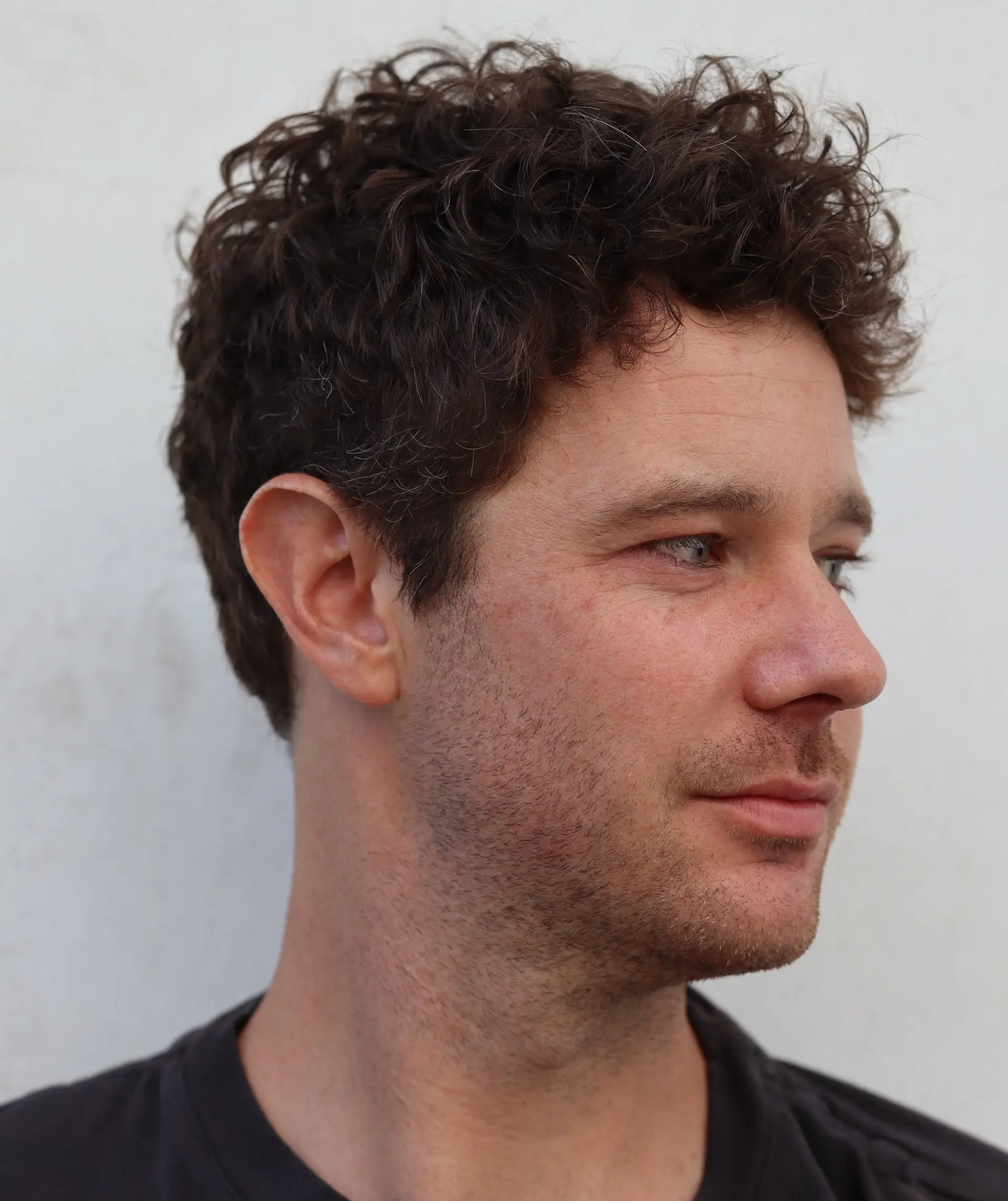 A textured short haircut tailored for natural curls and waves, cut cleanly around the ears with fuller, tousled volume on top. 1