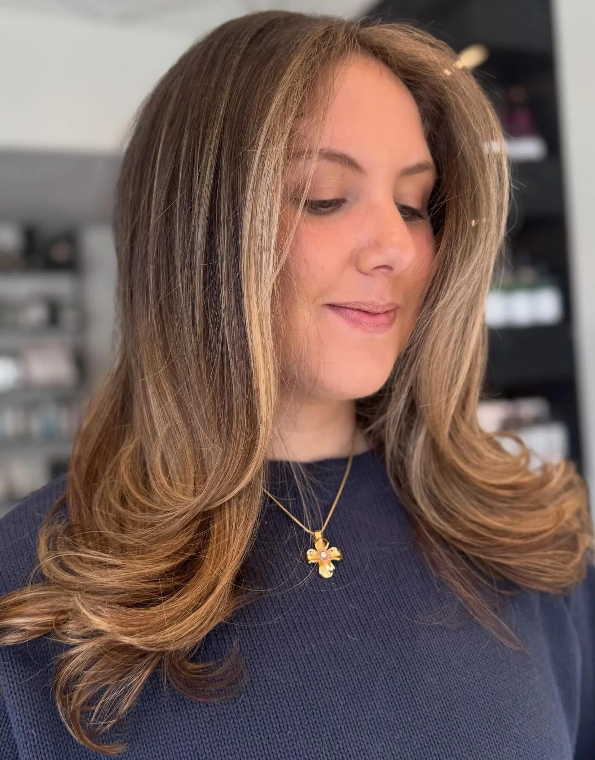 Medium-length layered cut styled into a bouncy blowout with curled flipped ends and bright face-framing blonde highlights. 1