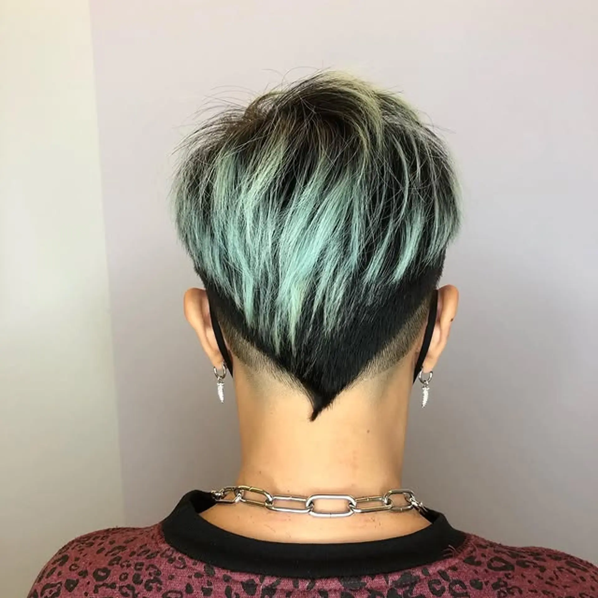 A short pixie cut with an undercut and mint green highlights. 1
