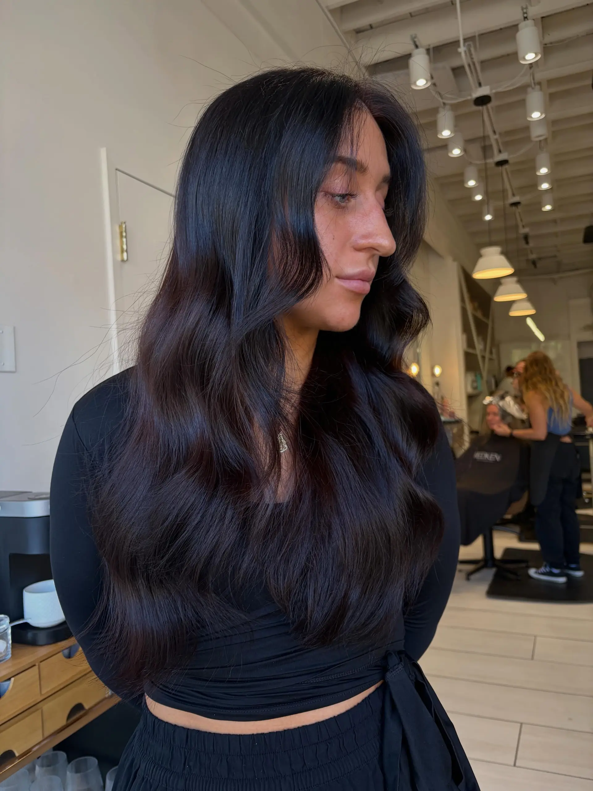 Long, glossy deep cherry cola brunette hair styled in smooth, voluminous waves. 1
