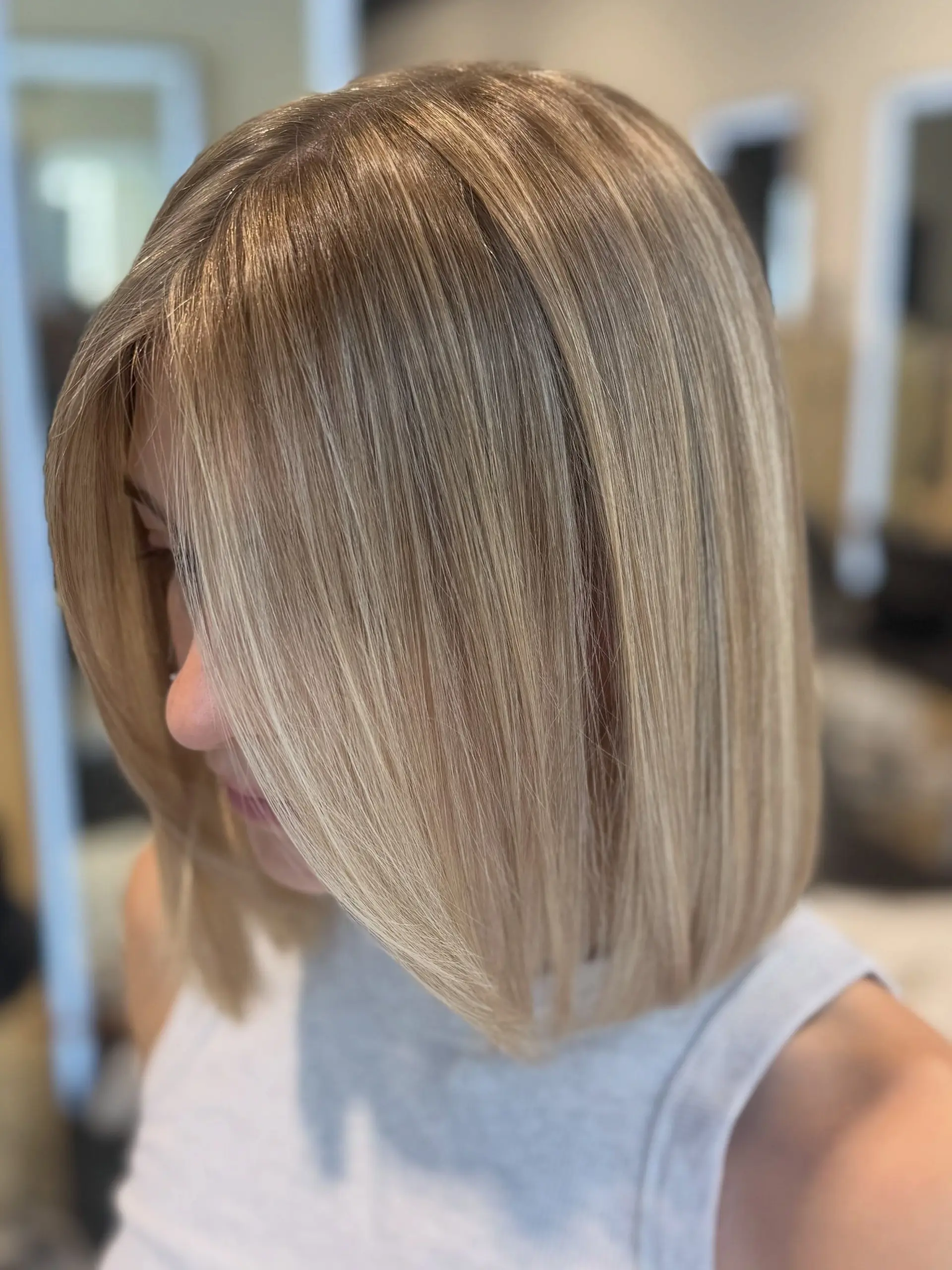 A structured blunt bob cut styled straight with fine, seamlessly blended dimensional blonde highlights. 1