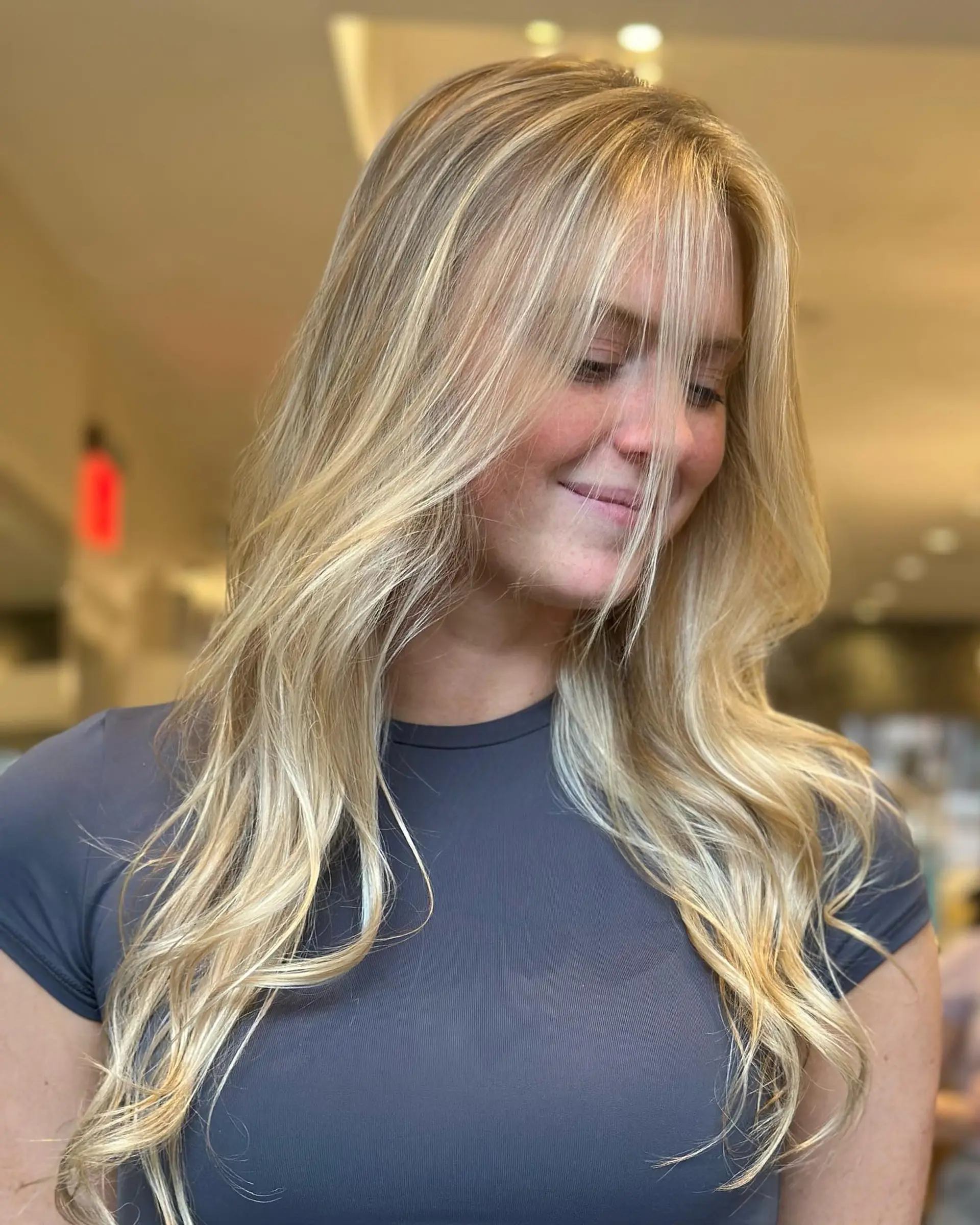 Long, multi-dimensional blonde hair styled in soft, relaxed waves with a light, wispy face-framing fringe. 1