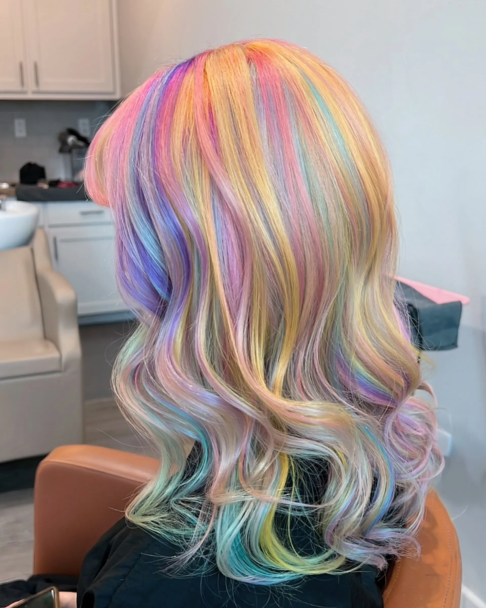 This eye-catching hairstyle showcases medium-length wavy hair adorned with a full spectrum of pastel rainbow colors, blended seamlessly for a magical, vivid, and whimsical unicorn effect. 1