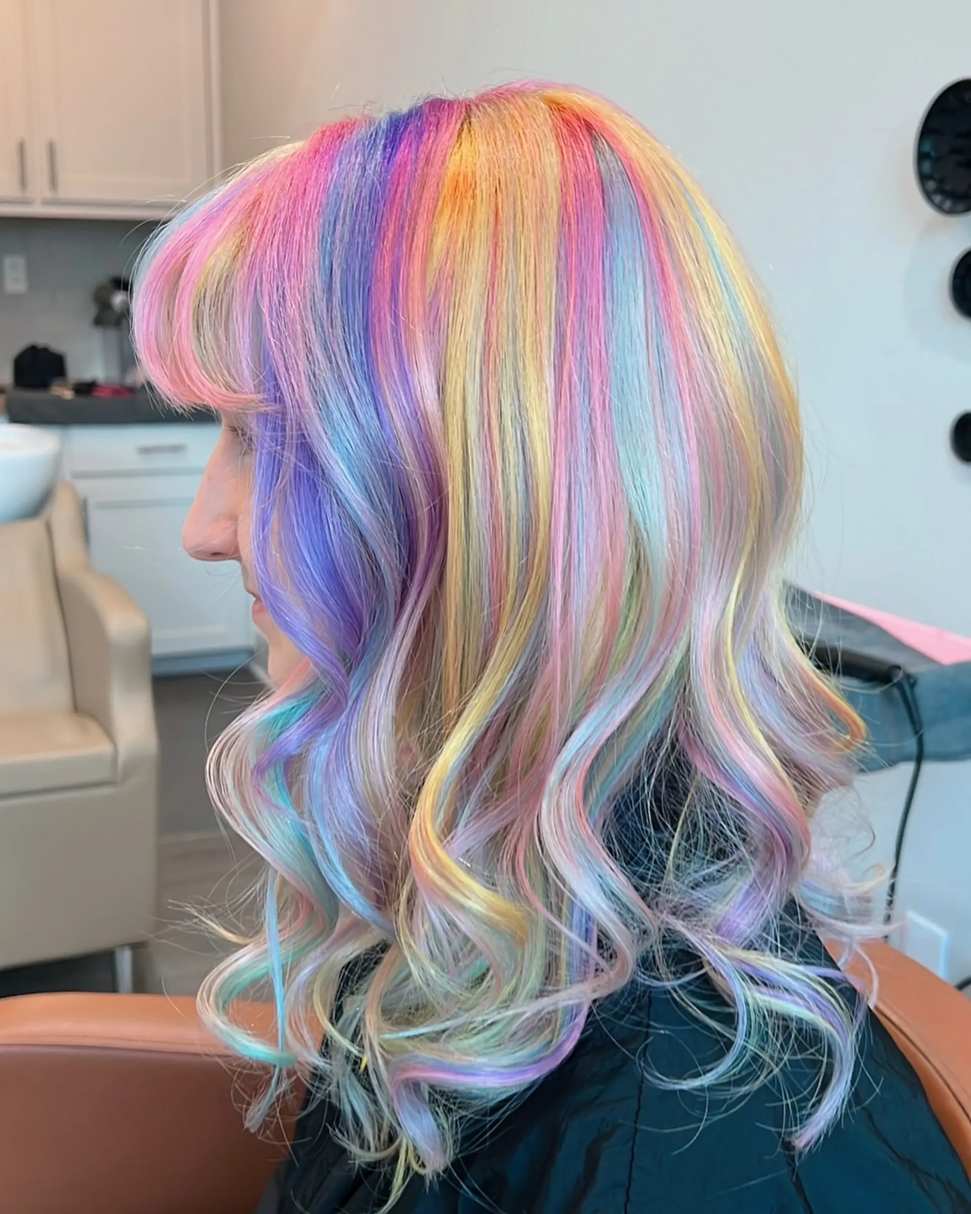 This eye-catching hairstyle showcases medium-length wavy hair adorned with a full spectrum of pastel rainbow colors, blended seamlessly for a magical, vivid, and whimsical unicorn effect. 4