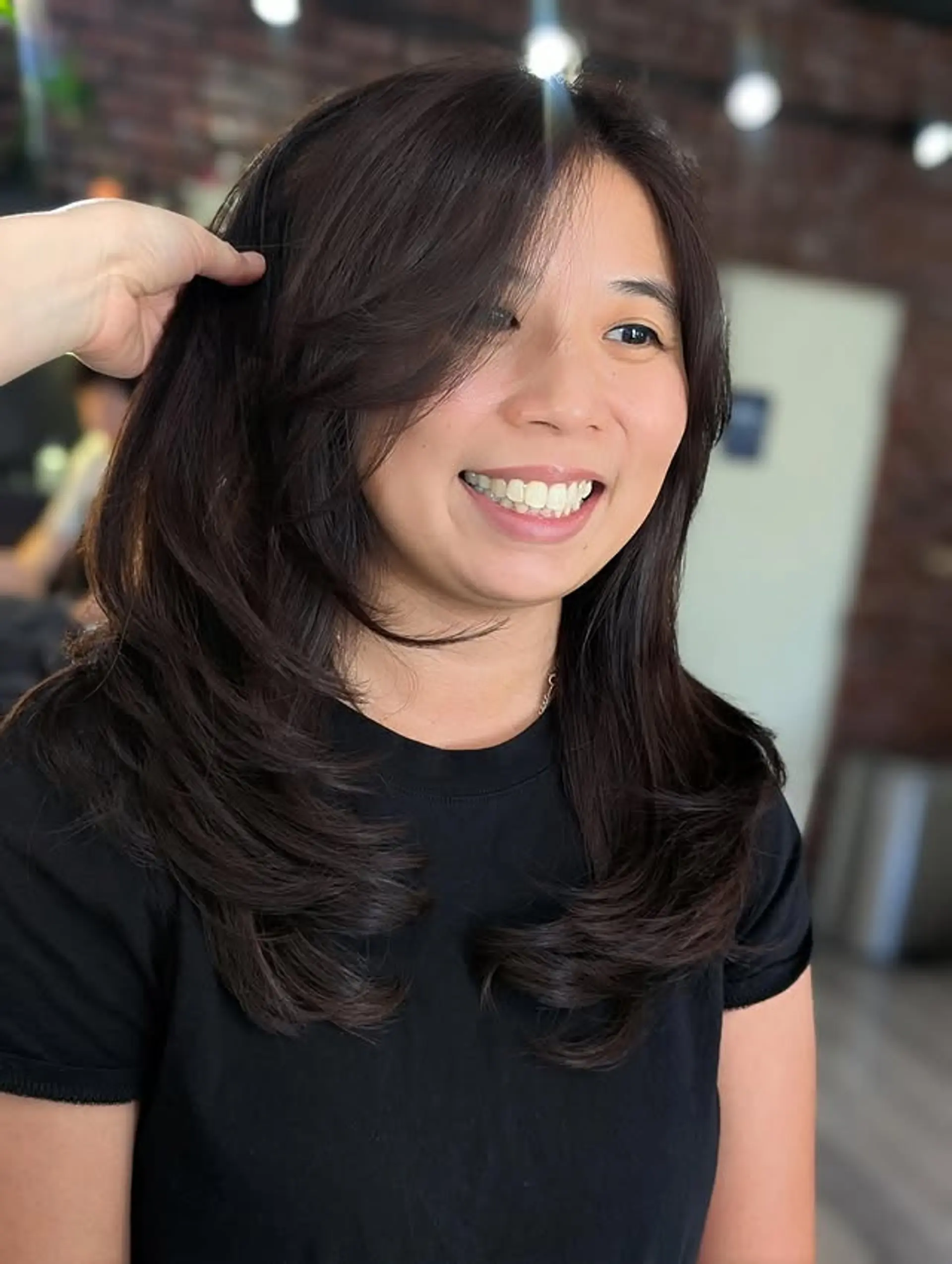 A stunning medium-length layered cut with gentle C-curls at the ends, complemented by soft, side-swept bangs for a graceful, voluminous, and face-framing effect. 1