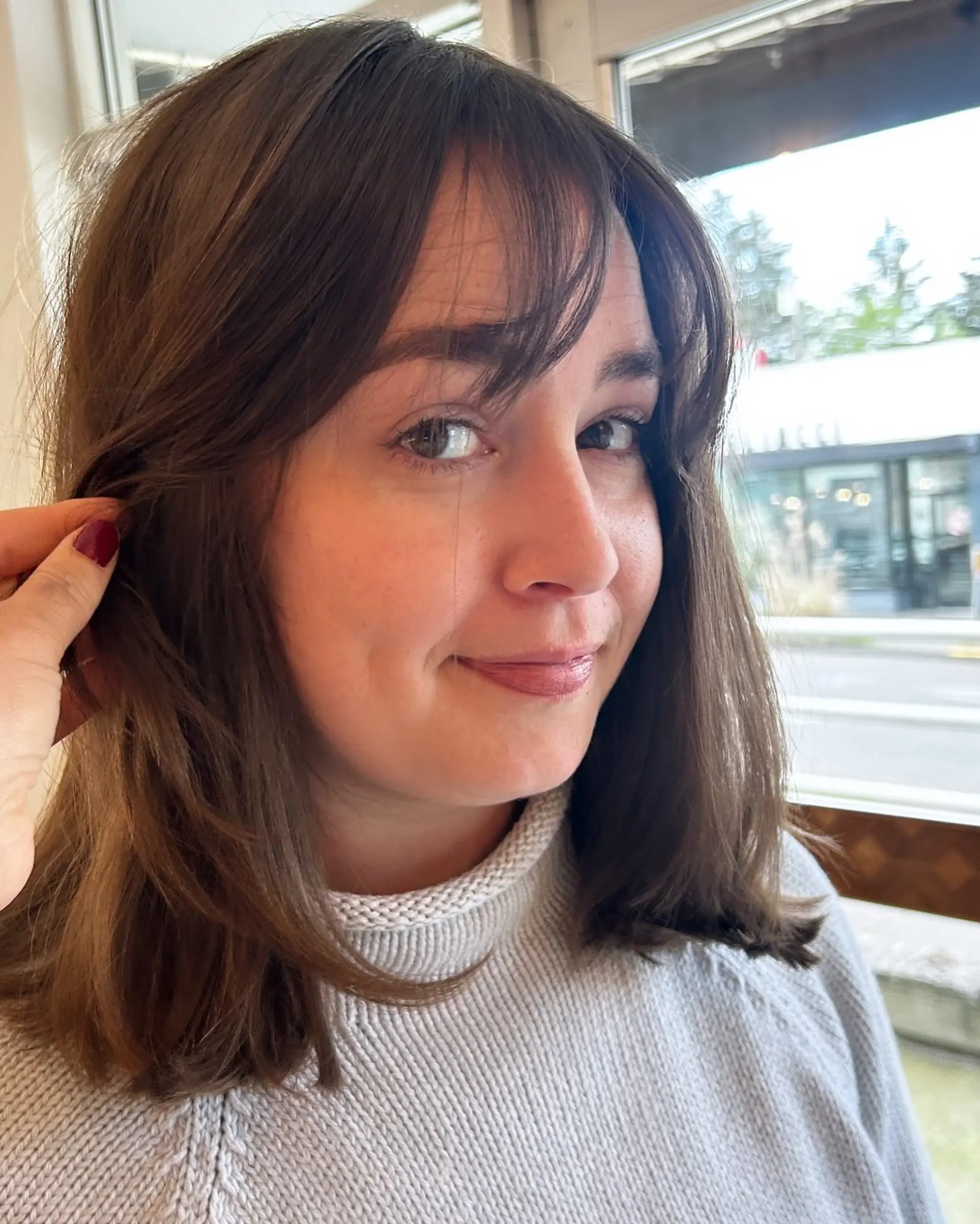 Collarbone-length brunette lob with soft, face-framing layers and wispy curtain bangs. 1