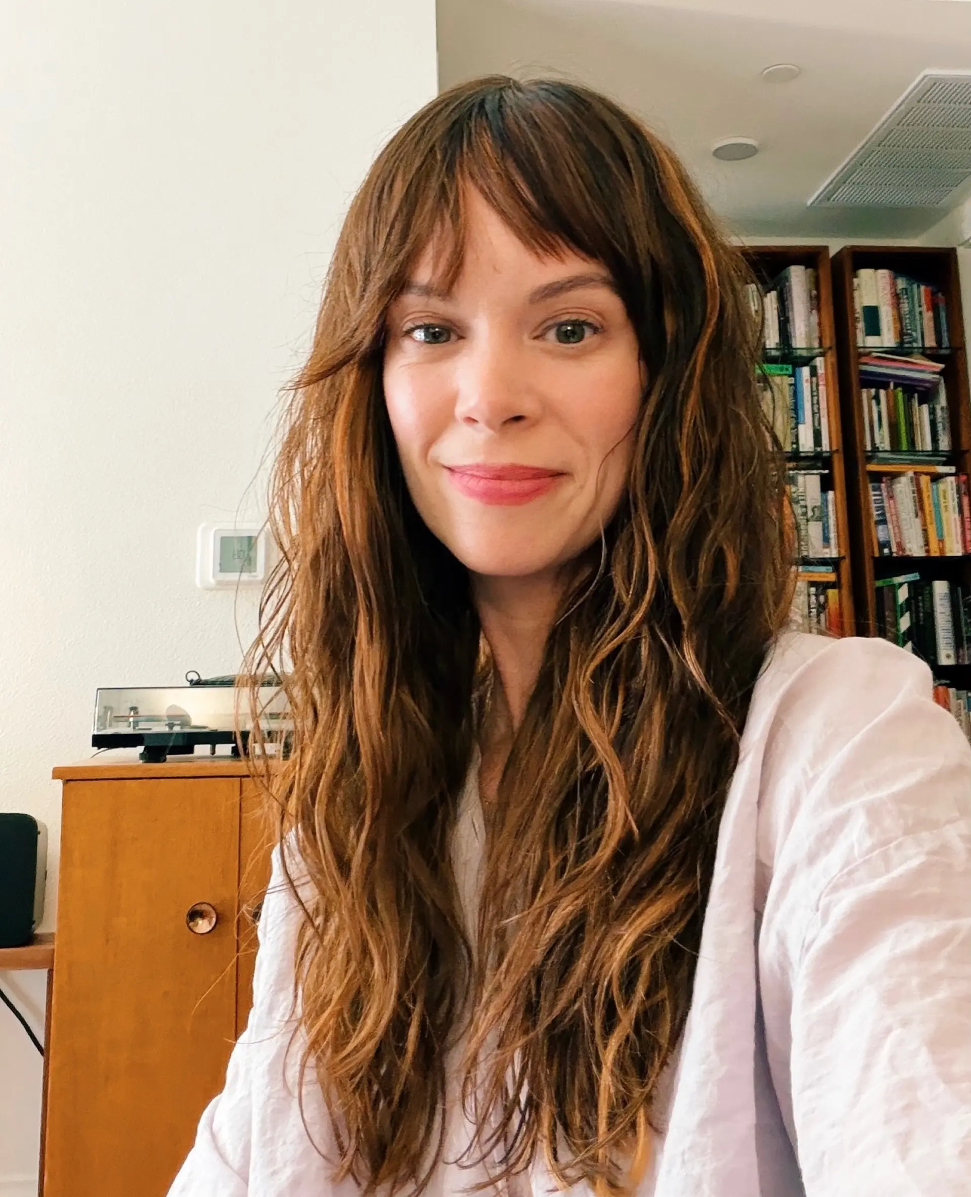 Long tousled wavy hair with dimensional honey brown highlights and wispy curtain-style bangs. 1