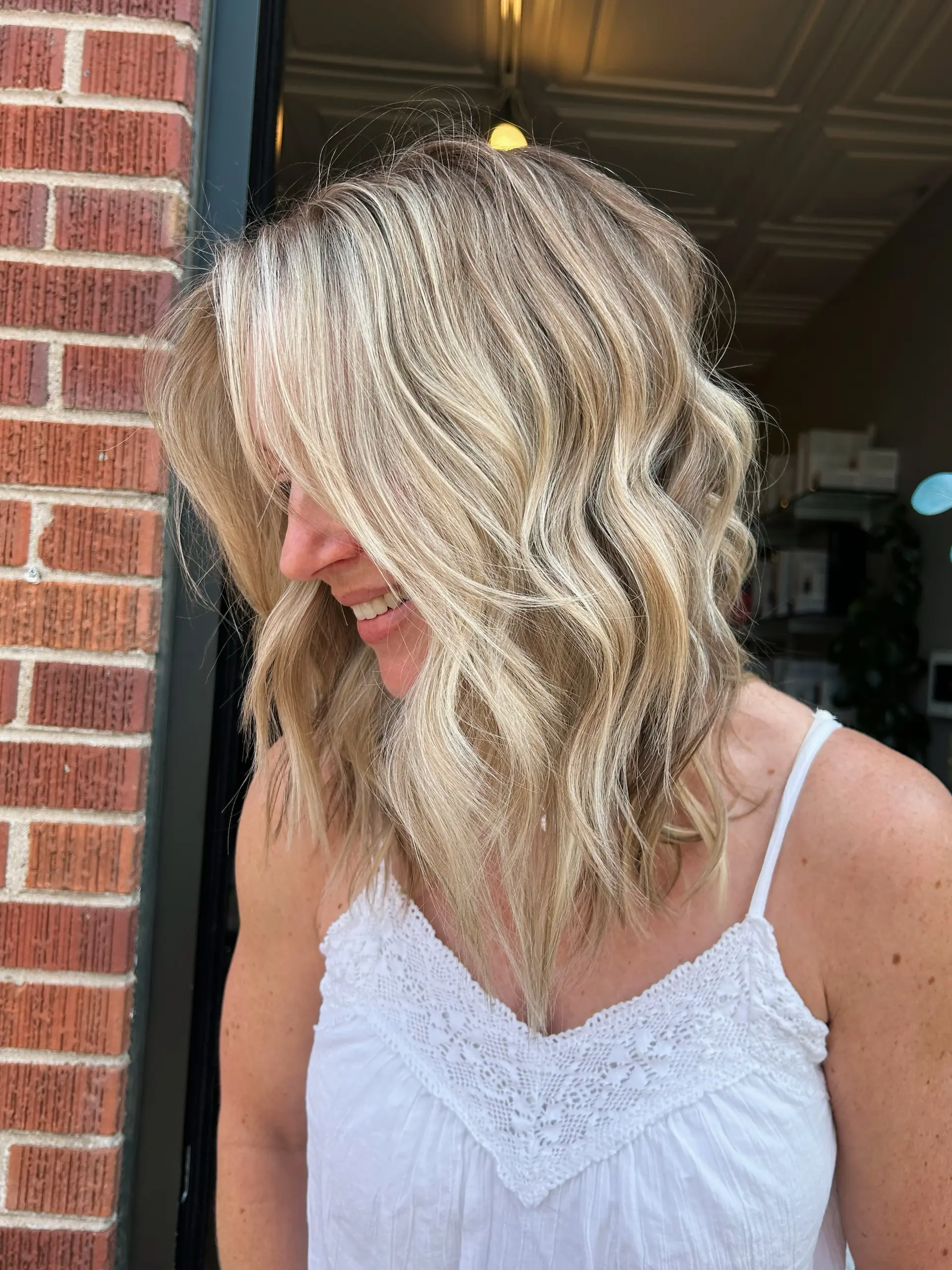 A textured medium-length lob styled with loose, relaxed waves and dimensional blonde highlights. 1
