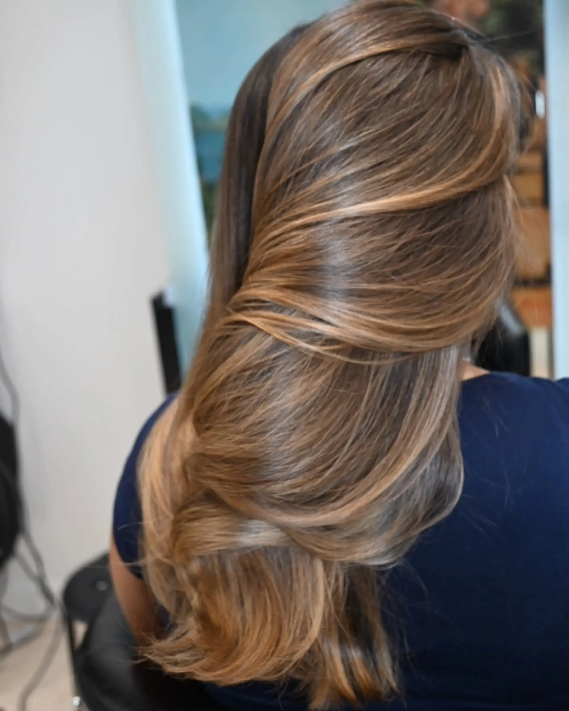 Long silky soft waves featuring dimensional honey blonde and caramel highlights. 1