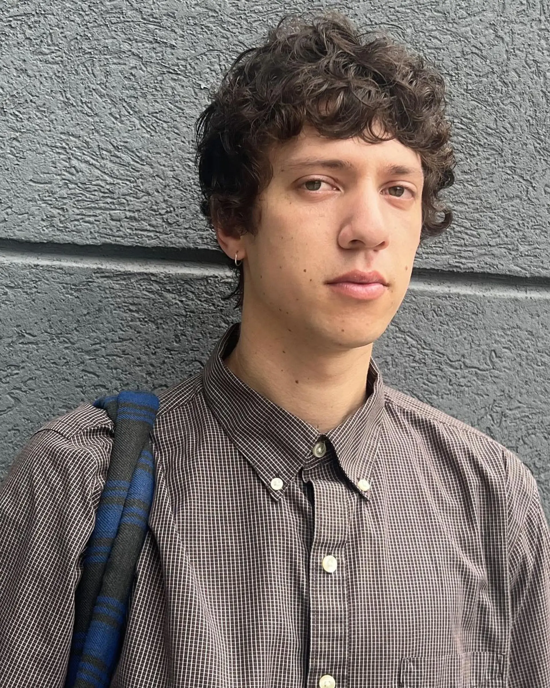 Short, dark brown curly hair with a natural and tousled texture, offering a relaxed and casual appearance. 1