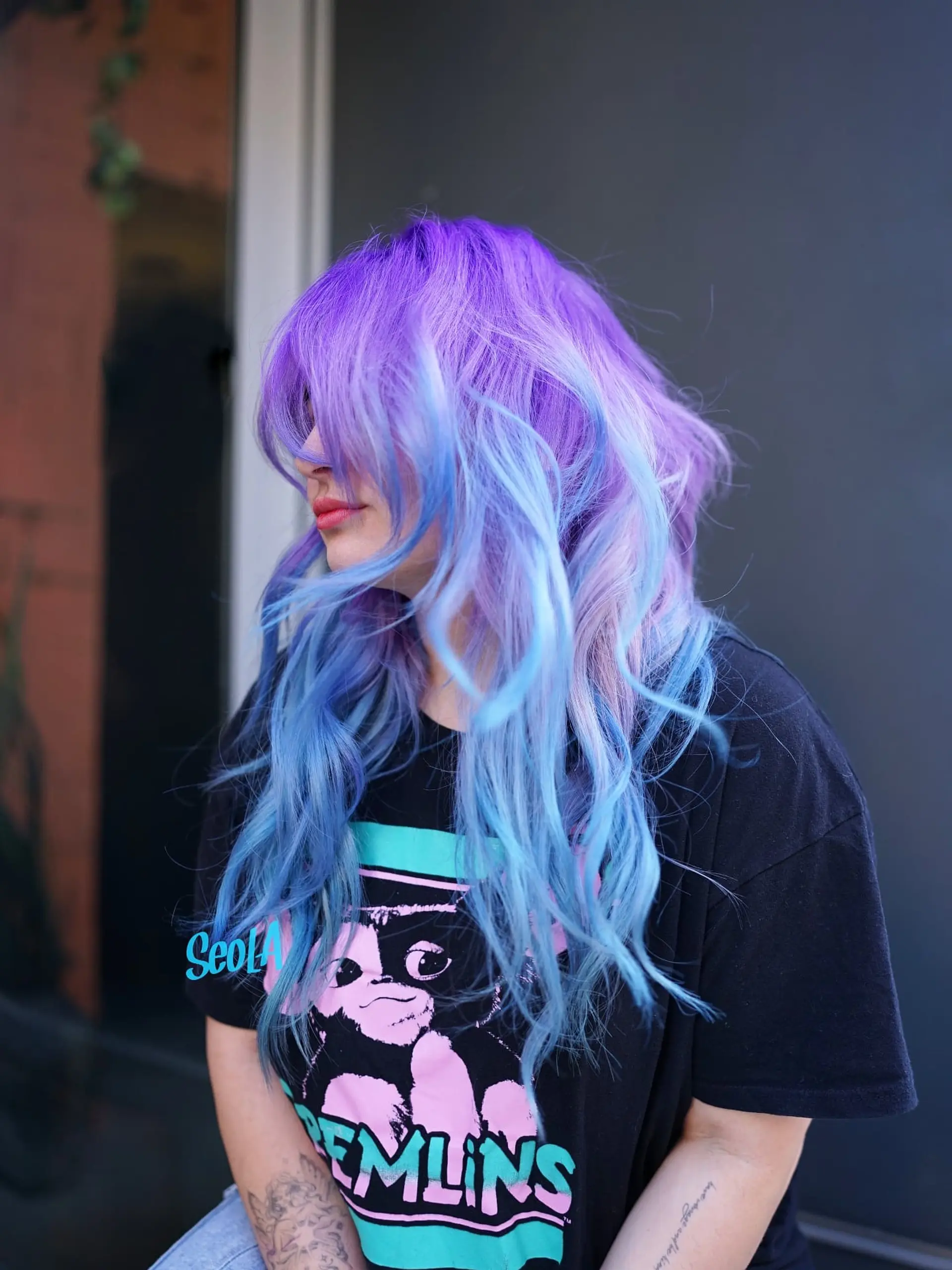 A vibrant vivid color melt featuring bright violet roots seamlessly blending into soft sky-blue and lavender tousled waves with face-framing fringe. 1