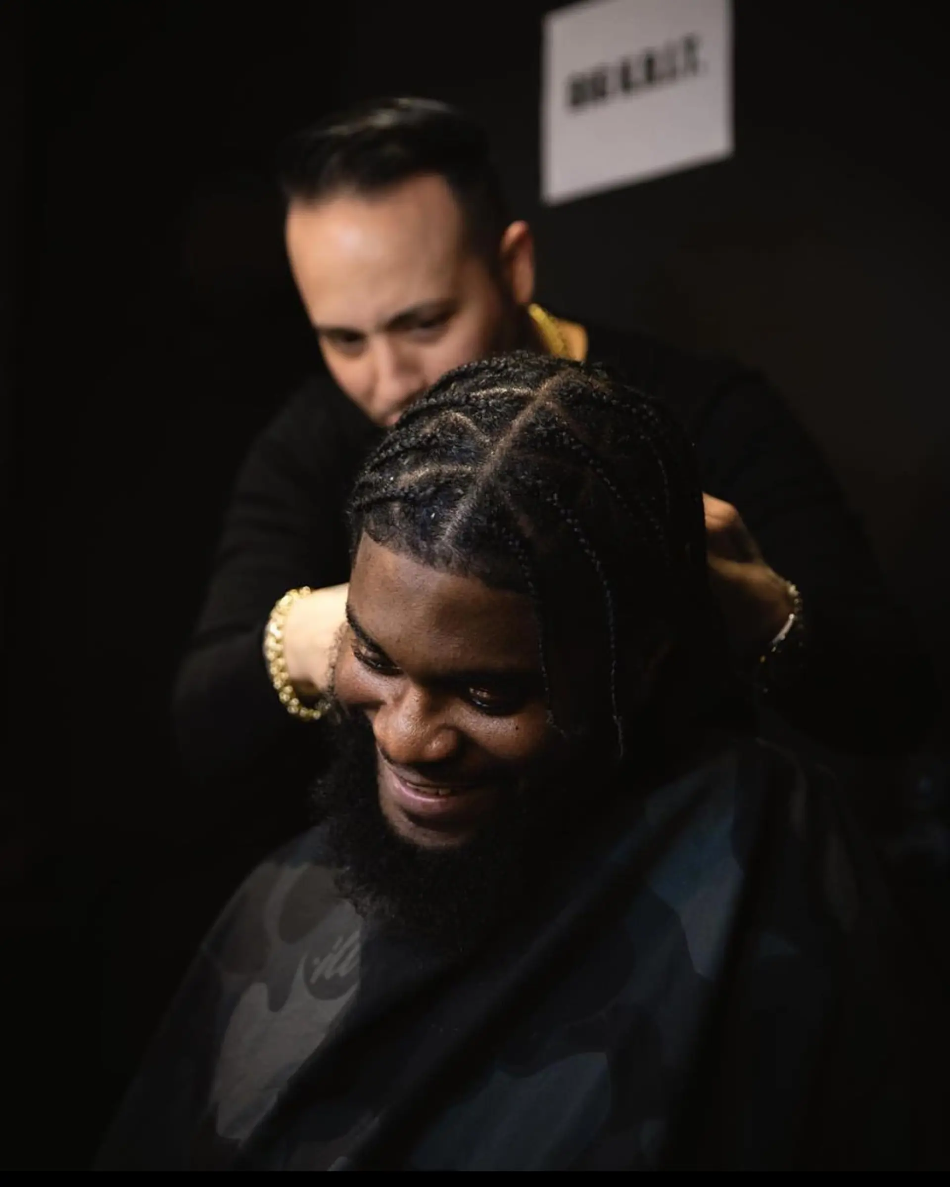 Neatly parted geometric braids styled close to the scalp, paired with a full natural beard. 1