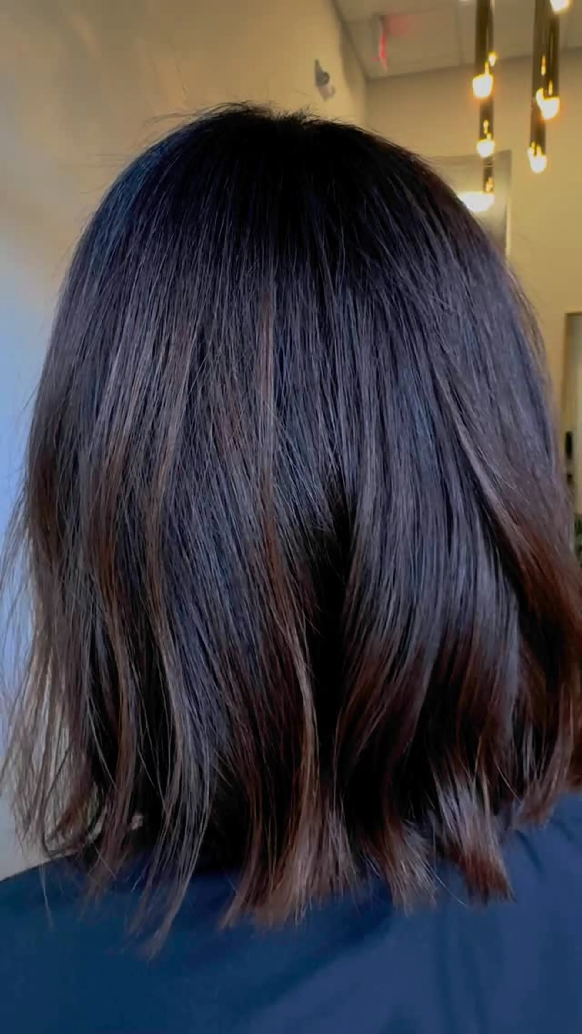A shoulder-length dark brunette lob featuring soft, textured bends and a rich, glossy finish. 1