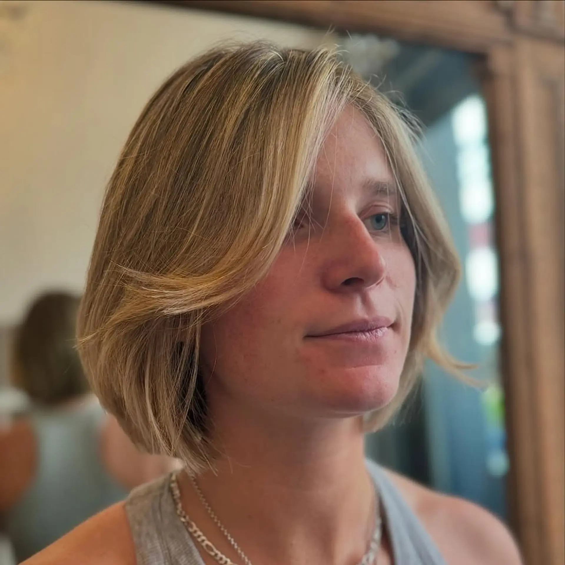 A short, straight bob with soft layers and a center part, featuring a warm blonde hue with honey highlights. 2