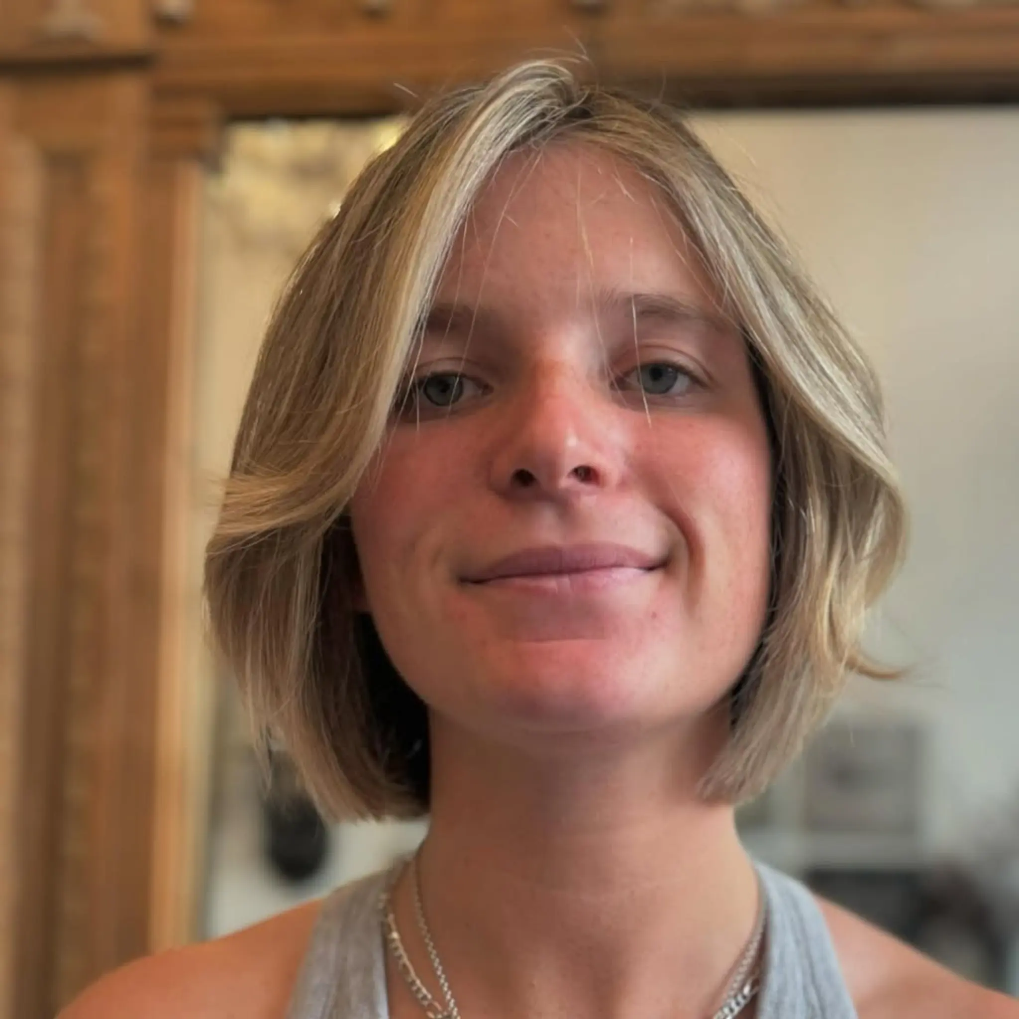 A short, straight bob with soft layers and a center part, featuring a warm blonde hue with honey highlights. 3