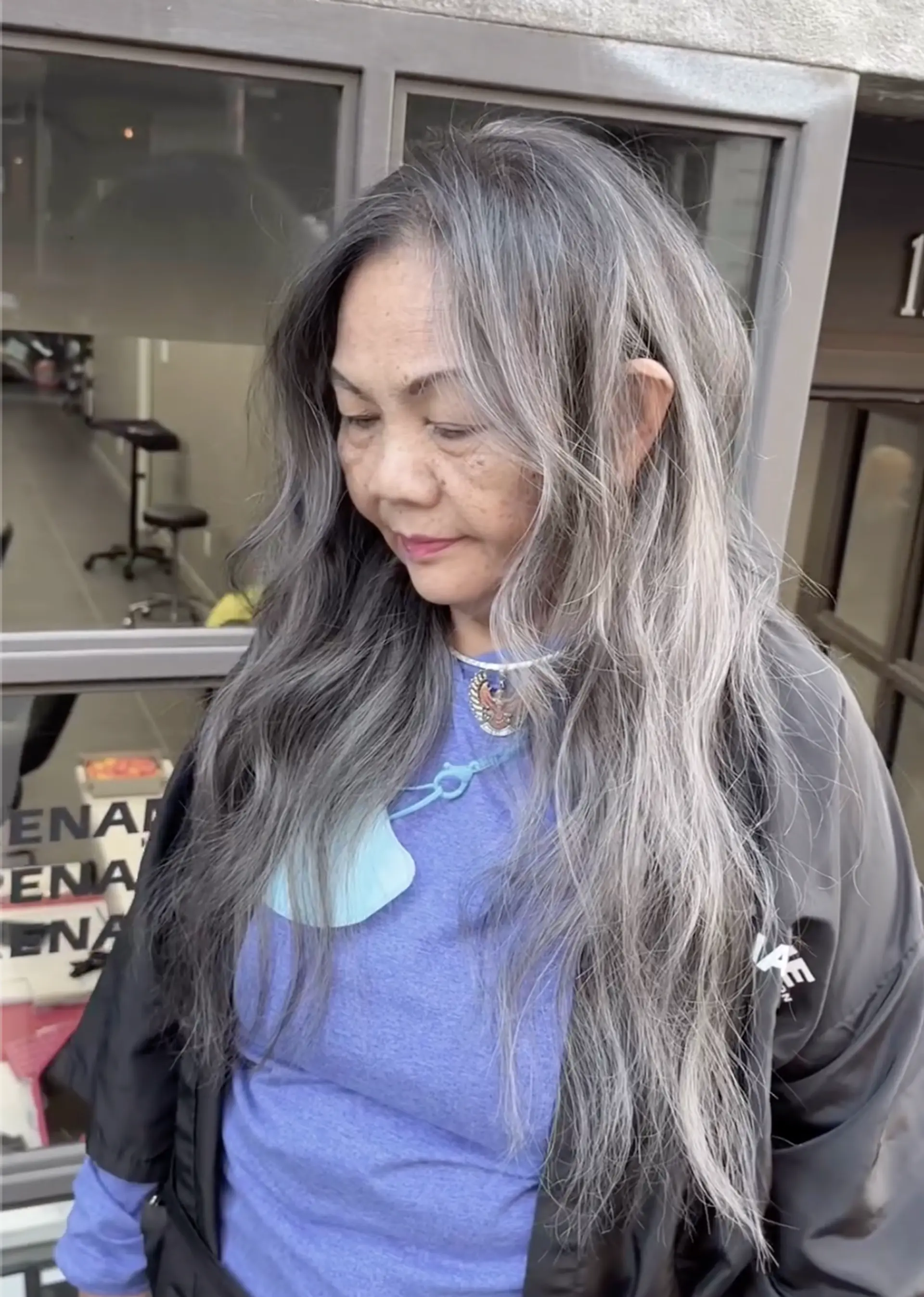 A beautifully wavy and long hairstyle with predominantly gray and silver highlights. The hair cascades naturally past the shoulders, creating a voluminous and flowing look with soft waves and layered texture. 1