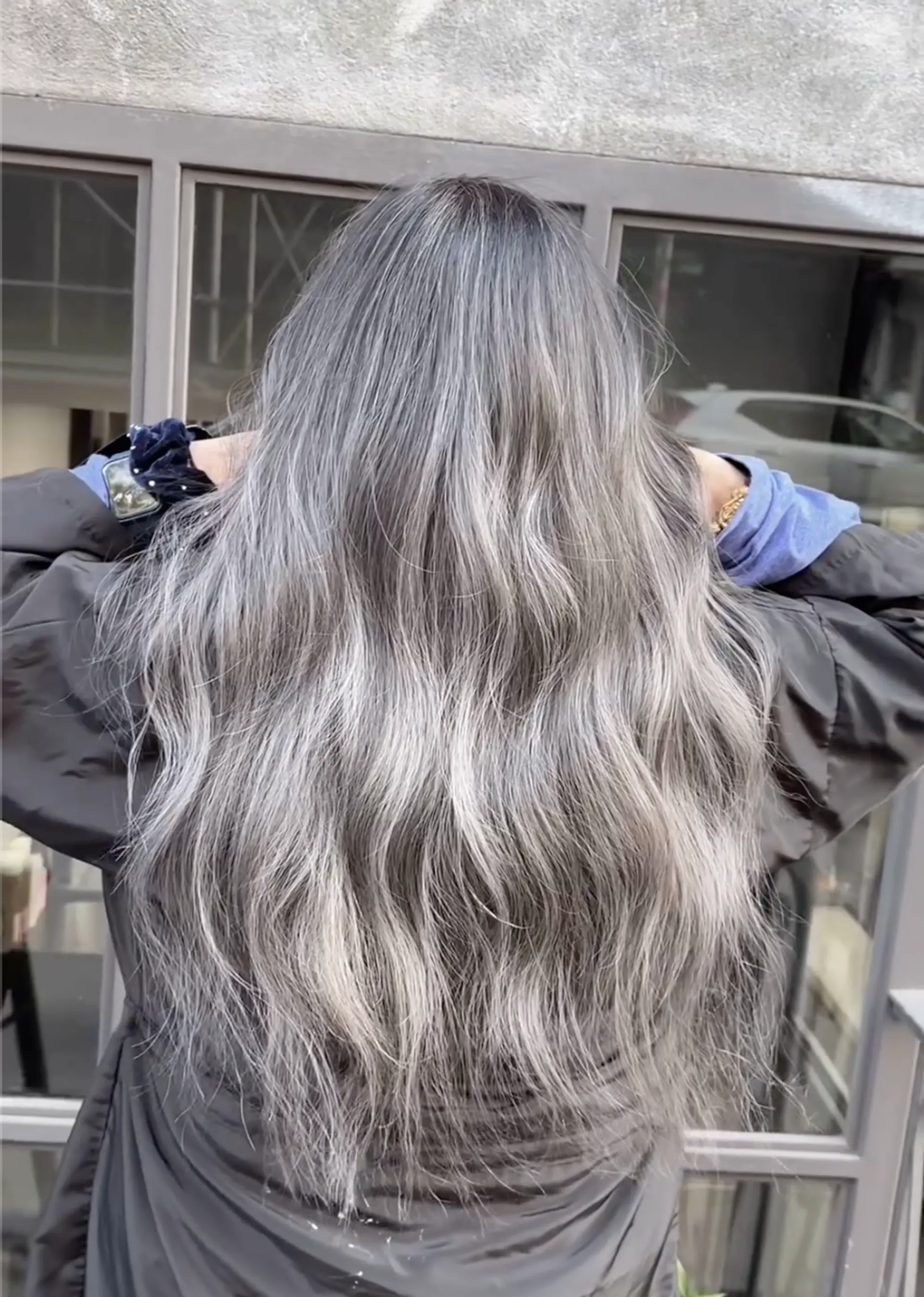 A beautifully wavy and long hairstyle with predominantly gray and silver highlights. The hair cascades naturally past the shoulders, creating a voluminous and flowing look with soft waves and layered texture. 2