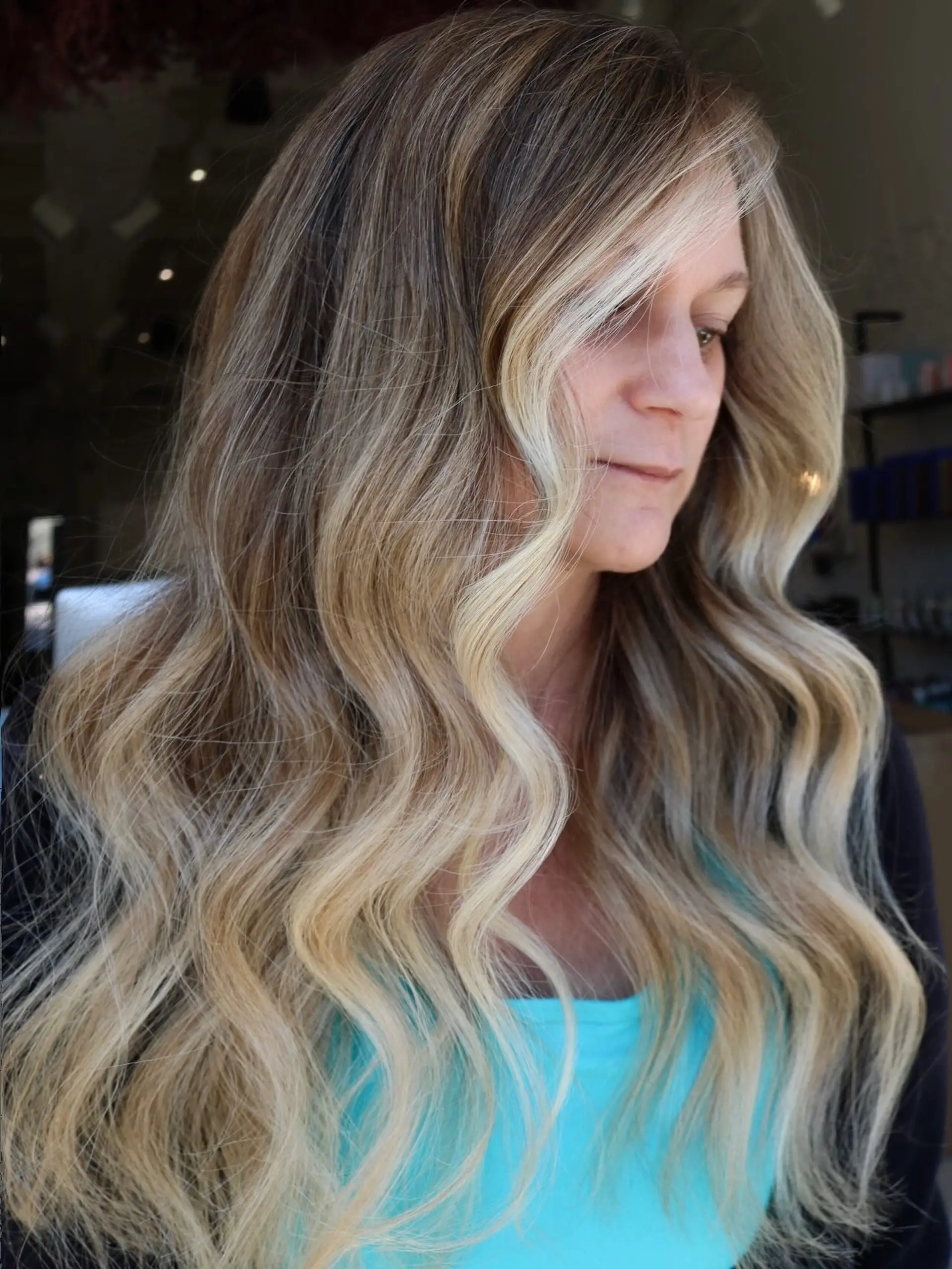 Long, flowing loose waves featuring a dimensional neutral blonde balayage with a bright, bold face-framing money piece. 1