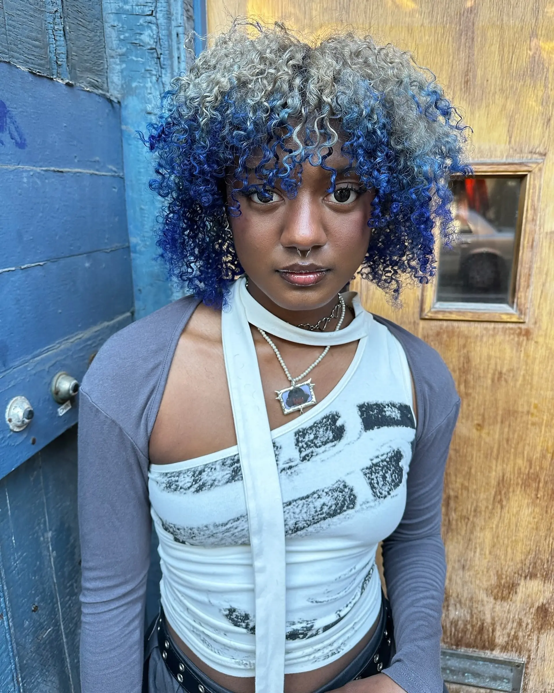 A defined tight curly bob with fringe featuring a striking contrast of vivid cobalt blue and icy silver-blonde. 1