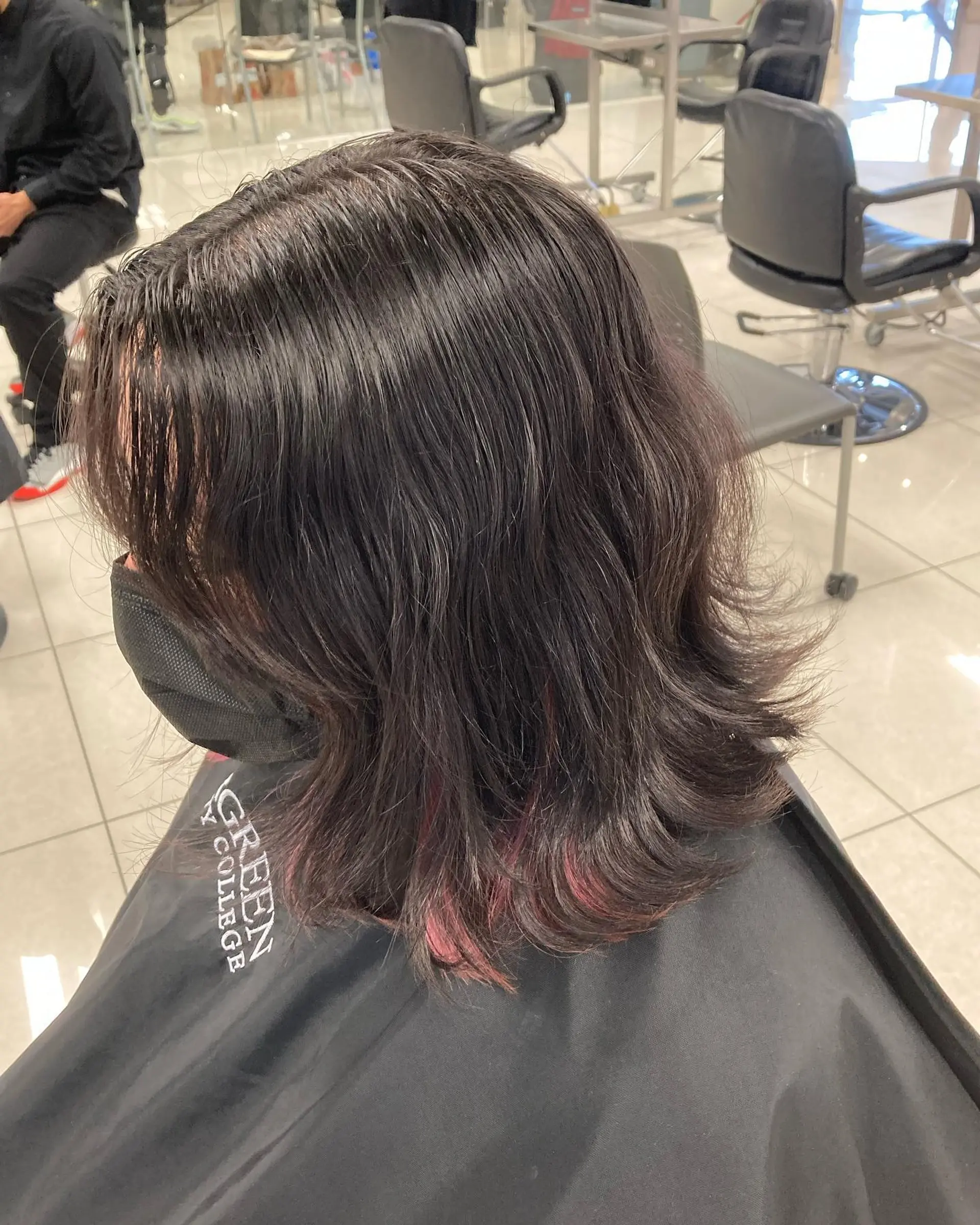 Medium-length dark brunette cut featuring textured layers with flipped ends and subtle peekaboo pink highlights. 1