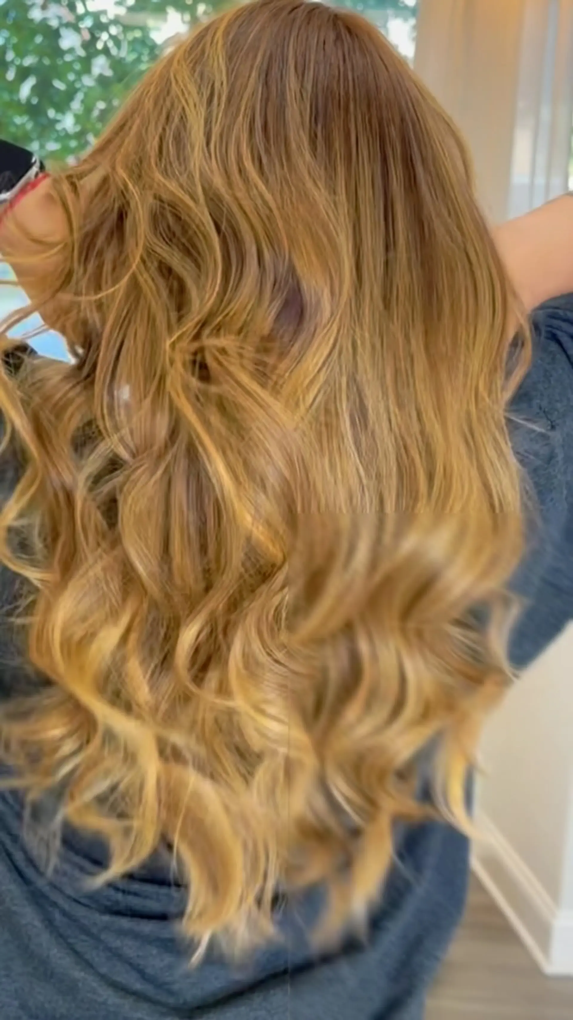 Long warm honey blonde hair styled with loose, voluminous waves and soft dimensional balayage highlights. 1